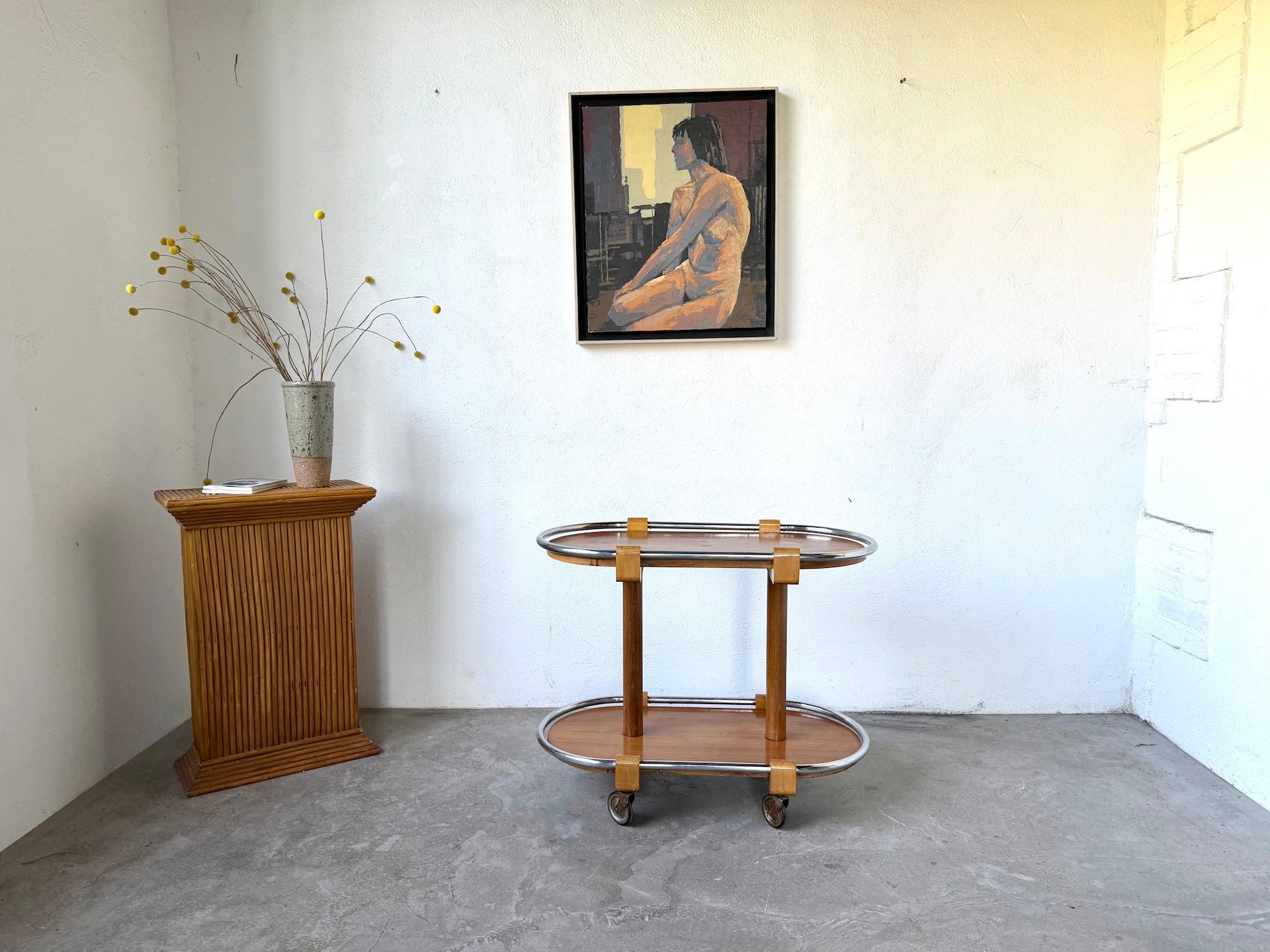 La MAISON LECAN présente ce chariot de bar Art déco des années 1930-40, avec une nette influence du Bauhaus.
Cette pièce raffinée associe deux plateaux ovales en bois à un cadre tubulaire en métal chromé, fixé par des ferrures en bois massif.

Le