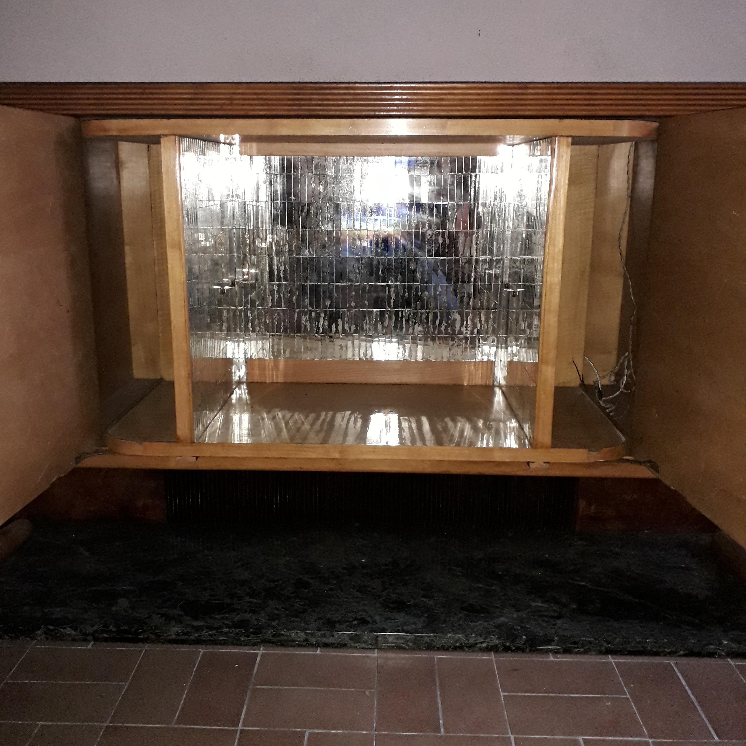 Art Deco bar credence by Vittorio Dassi, Milan.

The curved body, opens on eight drawers and discovers in its center a bar illuminating with sides covered with a mosaic mirror.
Connected by feet in massive Sycamore, the whole rests on a green marble