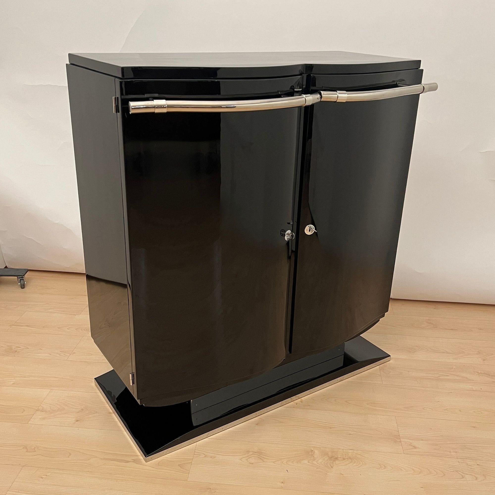 Extraordinaire meuble de bar ou de bar à boissons Art déco indépendant, datant de France/Paris vers 1930.
Bois de noyer laqué noir, poli brillant. Deux portes d'entrée incurvées avec un épais garde-corps chromé d'origine.
Portes intérieures en