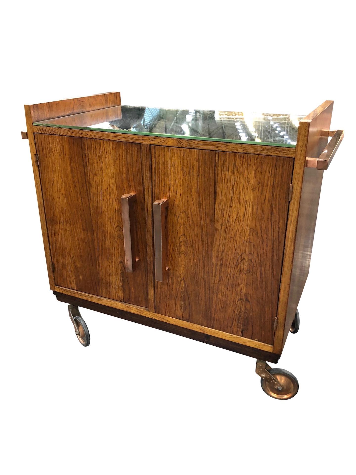 Art Deco bar trolley in style of Jacques Adnet 
Real wood veneer 
Handles and wheels in copper
To open on one side with double doors
Tabletop with old mirror (blind spots)
New mirror-tablet inside
Original Art Deco, France, 1930s 

Heavy! >>