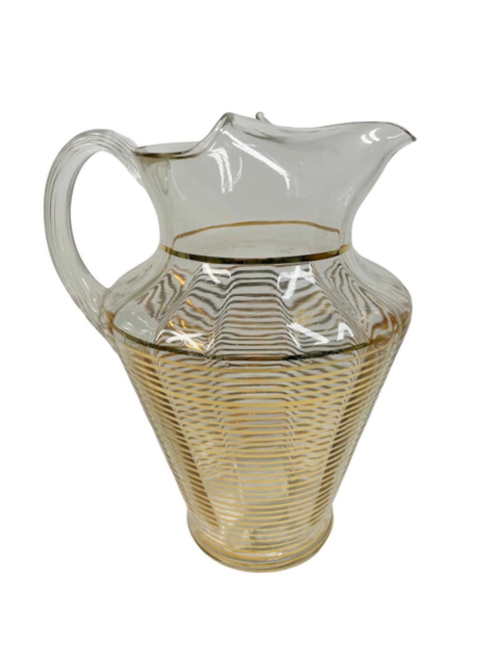 Art Deco water or bar pitcher of optically ribbed clear glass with narrow gold bands from the foot to the shoulder and an applied  reeded glass handle, the mouth of the pitcher is molded with an integral ice dam at the spout.