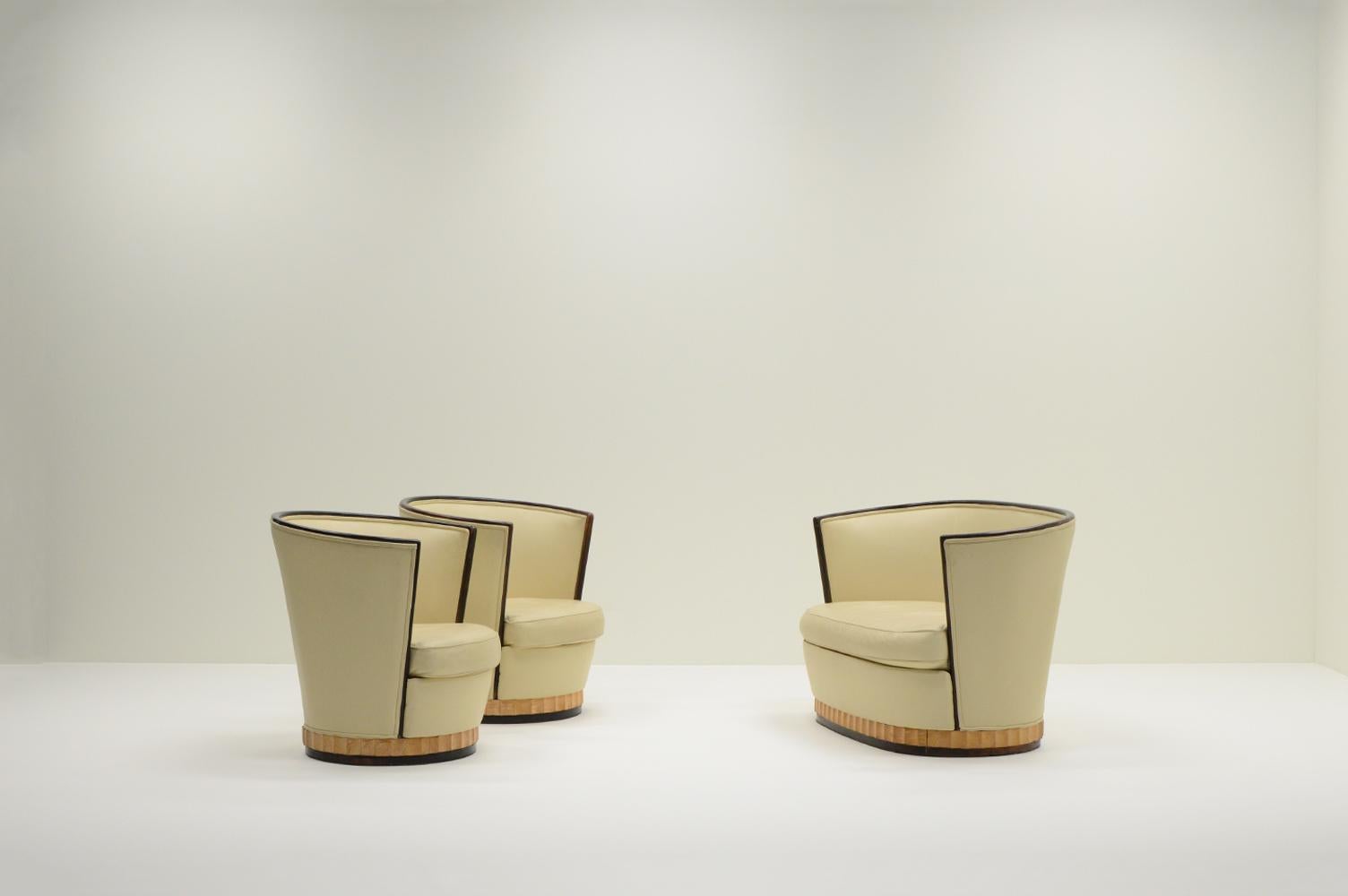Art Deco barrel chairs and sofa, France 1930s. Set of 2 armchairs and 1 two-seater. Reupholstered at one point in high quality cream white leather. Wooden base and armrests / trim. In good vintage condition. 

Measurements chair:
– Height: 81 cm
–