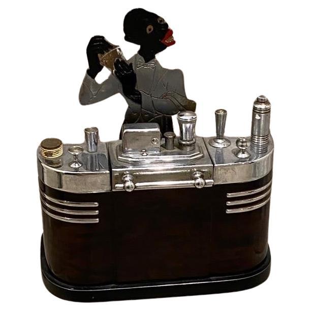A Ronson desk top Touch-Tip lighter featuring a Jazz era bartender shaking a martini behind his Streamlined Art Deco era Cocktail bar.
This Desk features a flint touch tip lighter for lighting cigars and cigarettes.. 
The top of the bar has several
