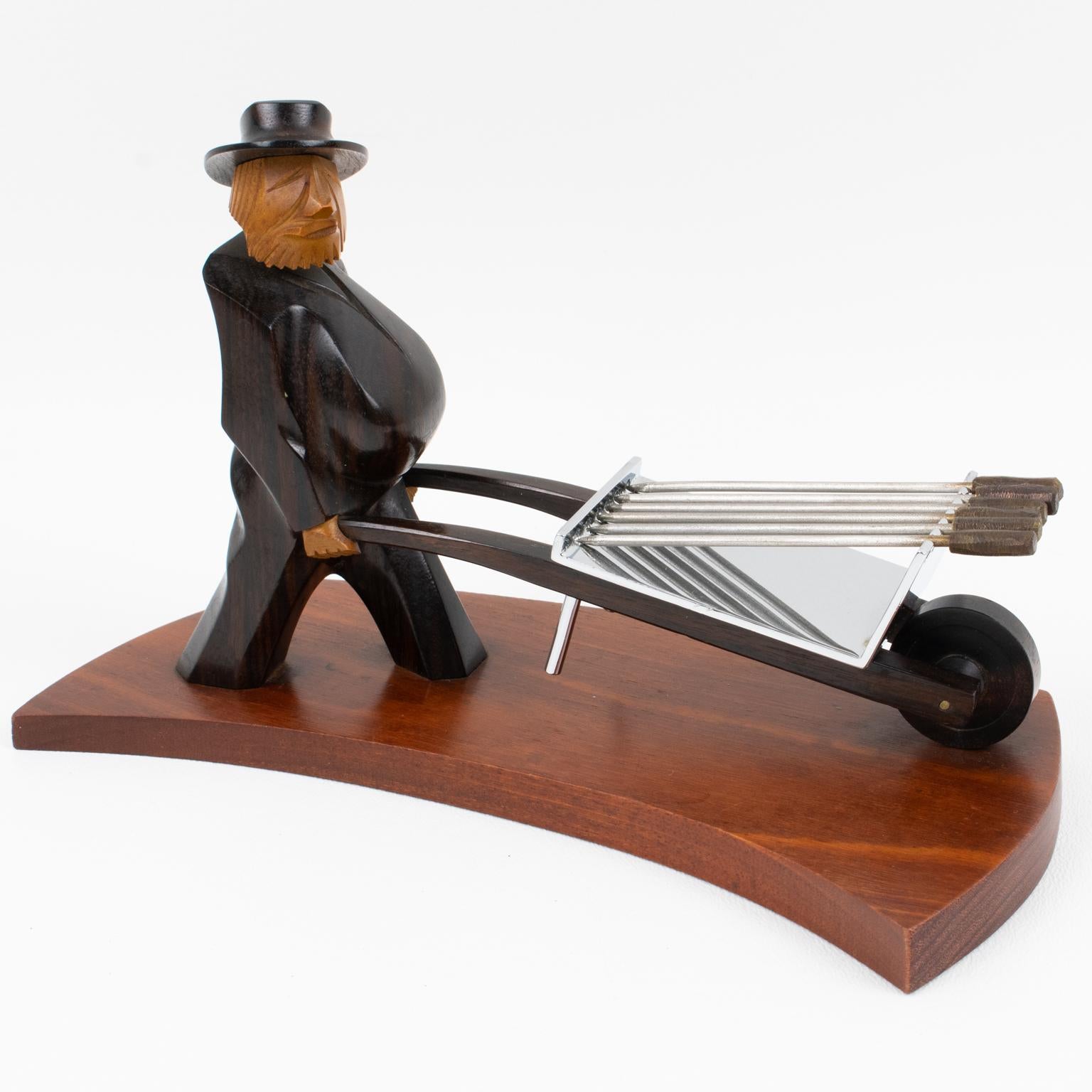 Questo splendido strumento da bar in stile Art Déco è stato progettato e realizzato negli anni '30 in Francia. L'accessorio cocktail picks raffigura un uomo che spinge una carriola con dei plettri. Il personaggio maschile è intagliato a mano con