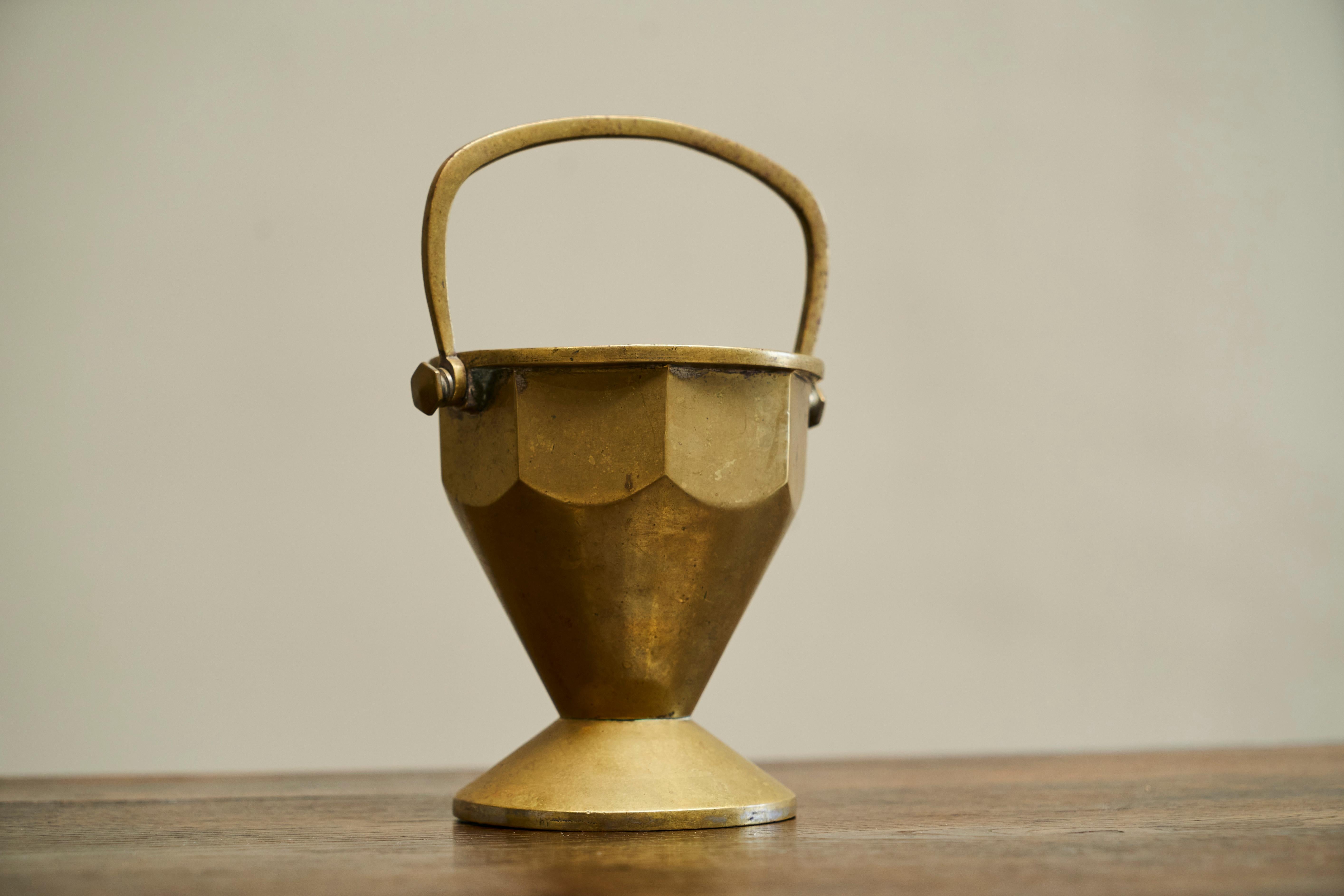 Eared Art Deco Basket in Patinated Solid Brass Early 20th Century.

Wonderful and very distinct basket / bowl / vase in patinated brass with handle. Great octagonal art deco design and a desirable patina. 

Would be great as a vase on a table, or