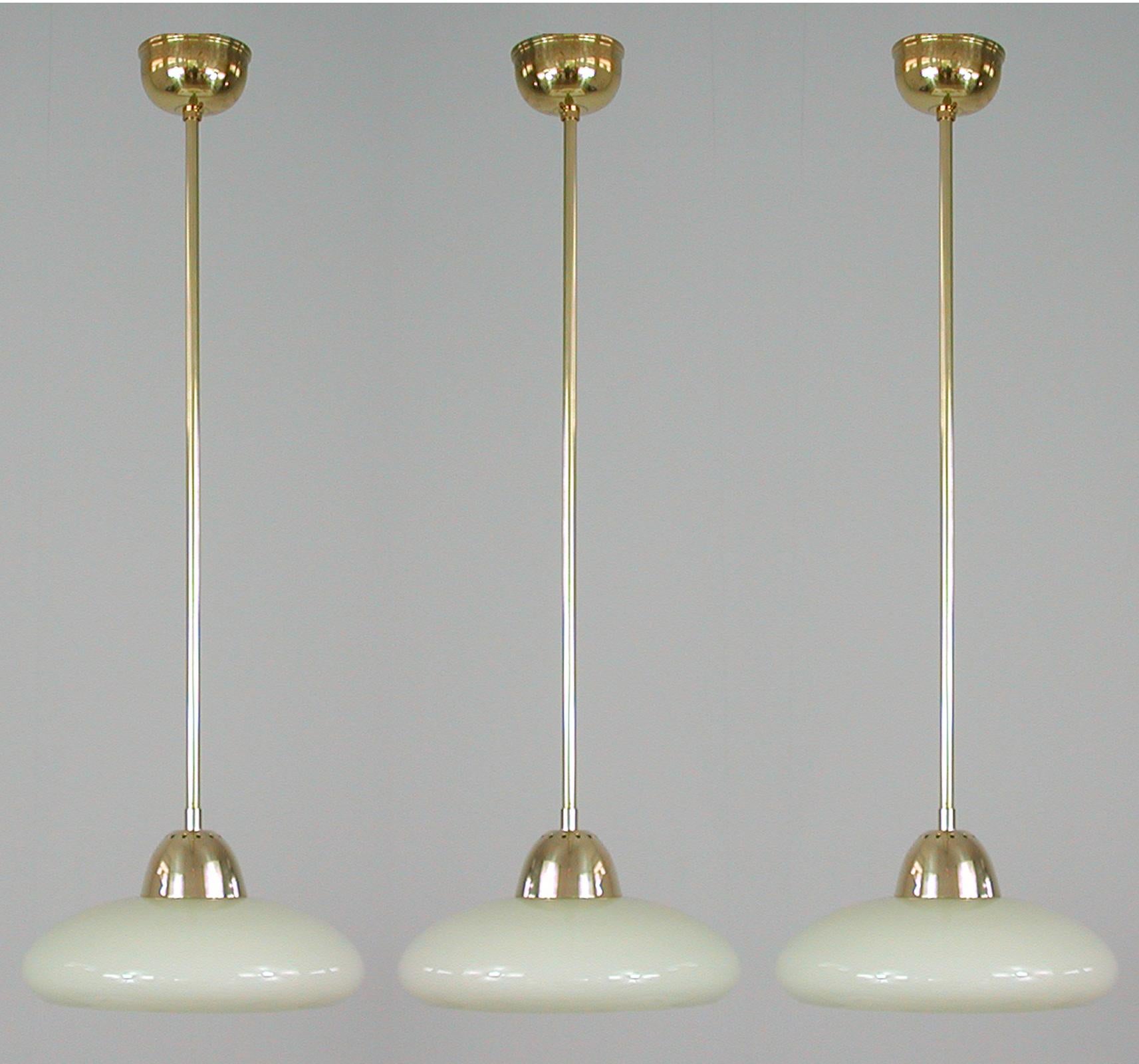 This elegant minimalist Art Deco pendant was designed and manufactured in Germany in the 1930s to 1940s during the Bauhaus period. 

The light features a round cream colored opaline lampshade and brass hardware. It requires one E27 bulb and has