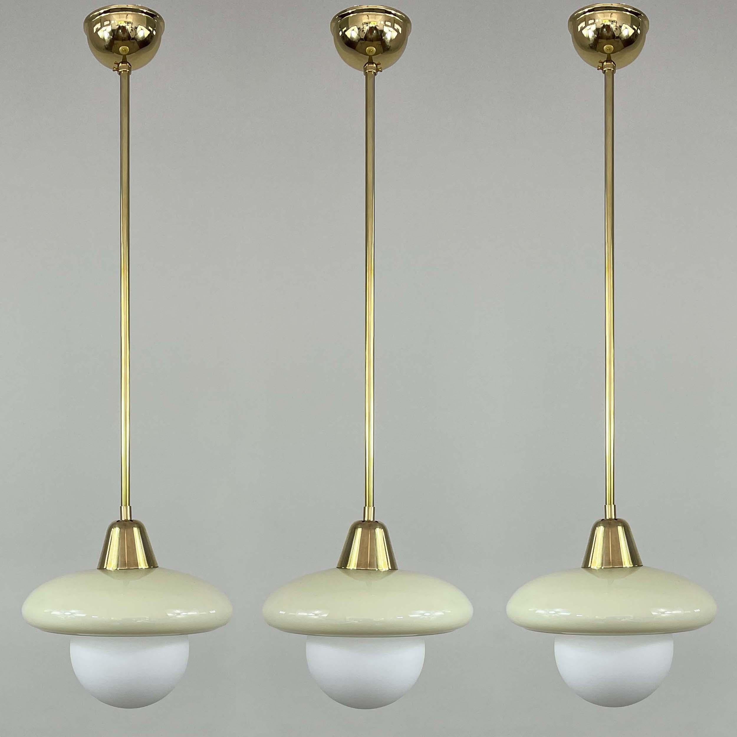 Diese elegante, minimalistische Art-Déco-Hängeleuchte wurde in den 1920er bis 1930er Jahren während der Bauhaus-Periode in Deutschland entworfen und hergestellt. 

Die Leuchte hat einen runden, cremefarbenen Opalin-Lampenschirm und Messingbeschläge.