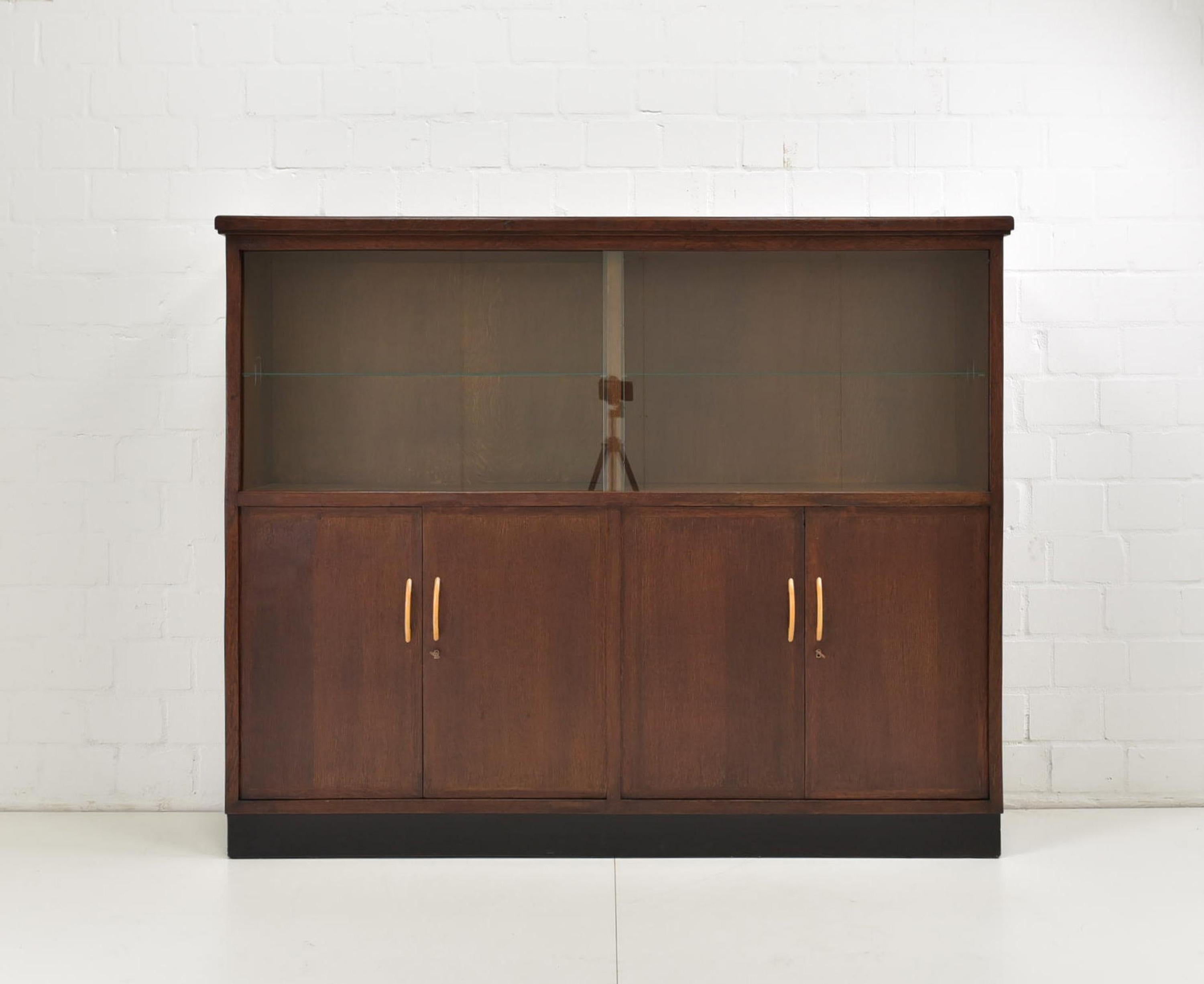 Display cabinet restored Art Deco / Bauhaus around 1940 Oak highboard

Features:
Model with 4 areas, each with a shelf
Showcase parts with glass sliding doors at the top four doors at the bottom
Geometric shape
Black base
Timeless, functional