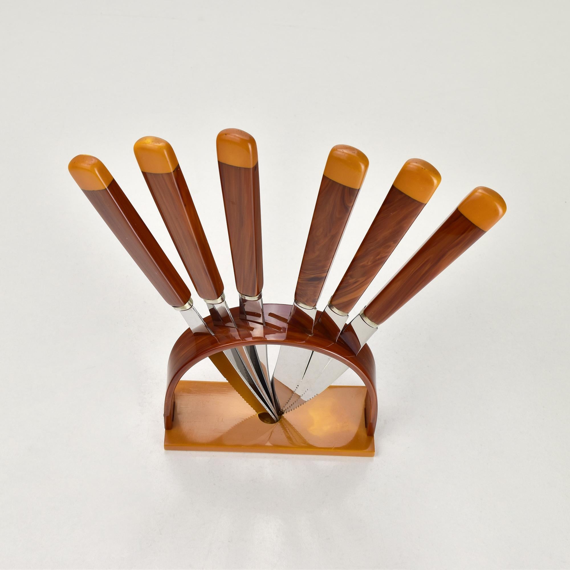 Elegante set di coltelli da frutta Art Deco degli anni '30, composto da sei coltelli in acciaio inossidabile con splendidi manici in bachelite/catalina color marrone marmorizzato e burro. Le maniglie presentano un ricco motivo a vortice, abbinato a