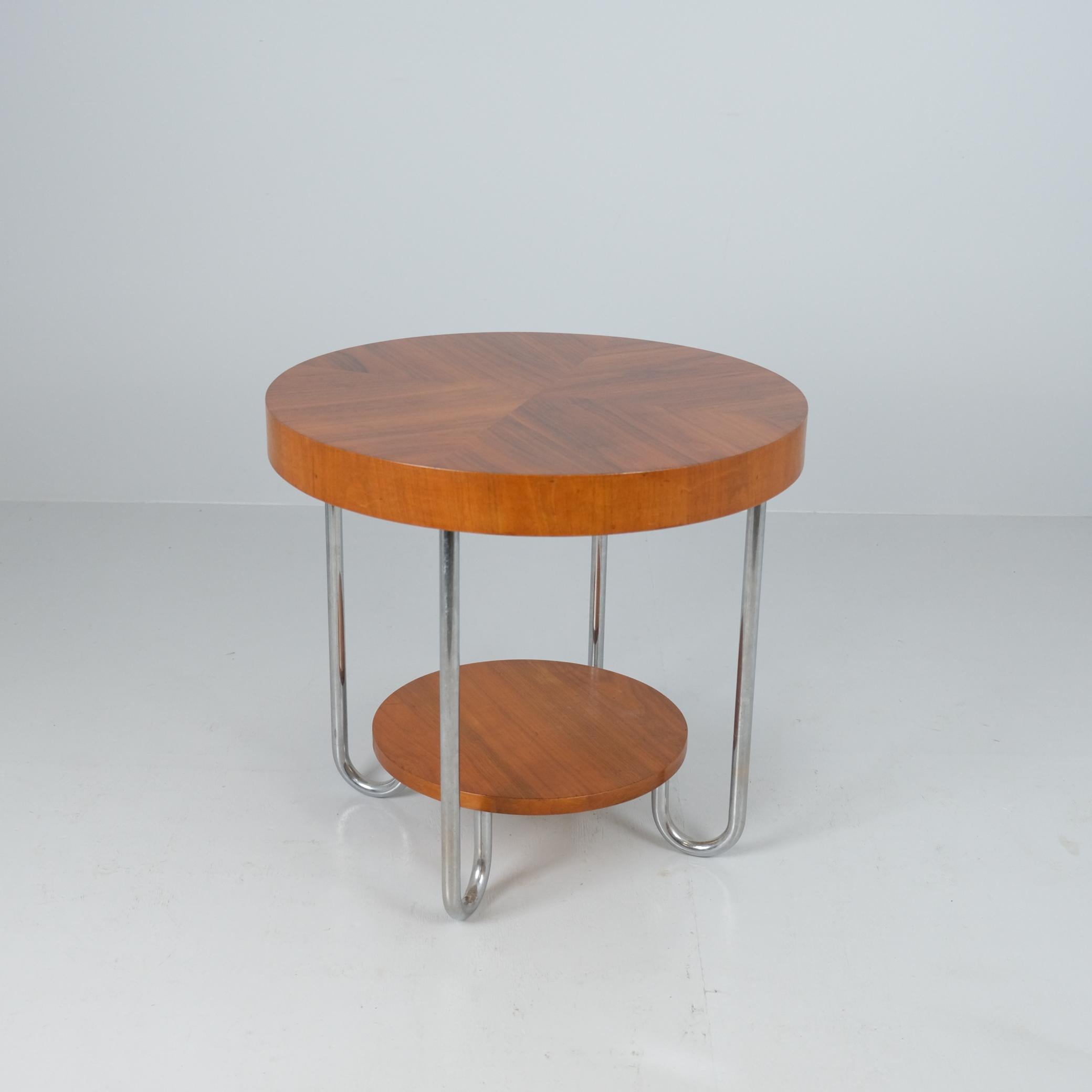 Un bellissimo tavolino Art Deco Functinalista con due piani in legno e gambe tubolari in acciaio cromato. I materiali si fondono con fascino e raffinatezza mostrando i charme della scuola funzionalista Bauhaus dell'inizio del XX secolo. Il tavolo è