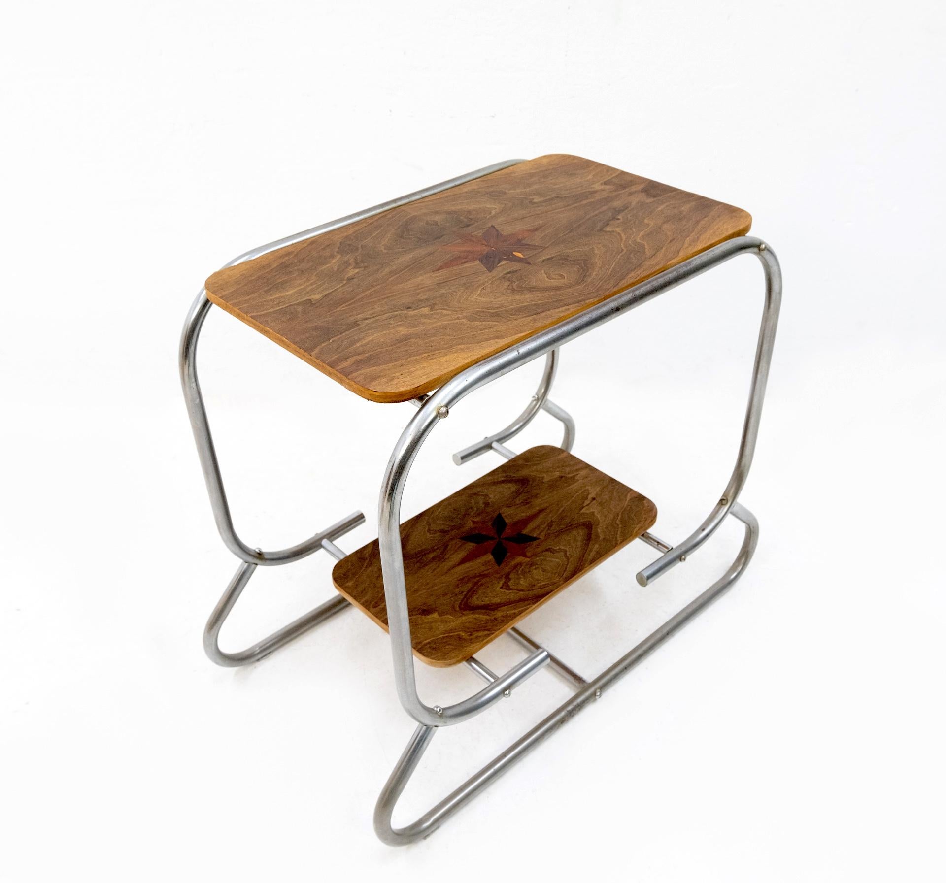 Art Deco two-tier side table. Chrome tube frame comes with walnut tops. With star
shaped intarsia, made off mahogany. Some damage on the top. See photo. Bauhaus, 1920-1930.