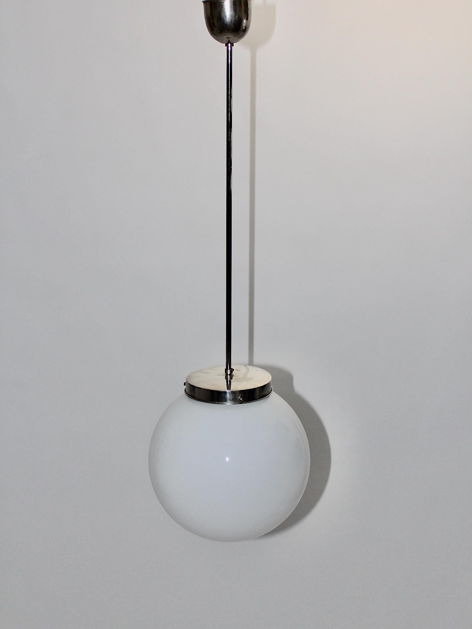 Bauhaus Art Deco vintage pendant hanging lamp chandelier with a 
nickel-plated metal base and an opal white ball glass shade 1930s, Germany.
This amazing Bauhaus Art Deco vintage pendant or hanging lamp is composed of a nickel-plated metal stem and