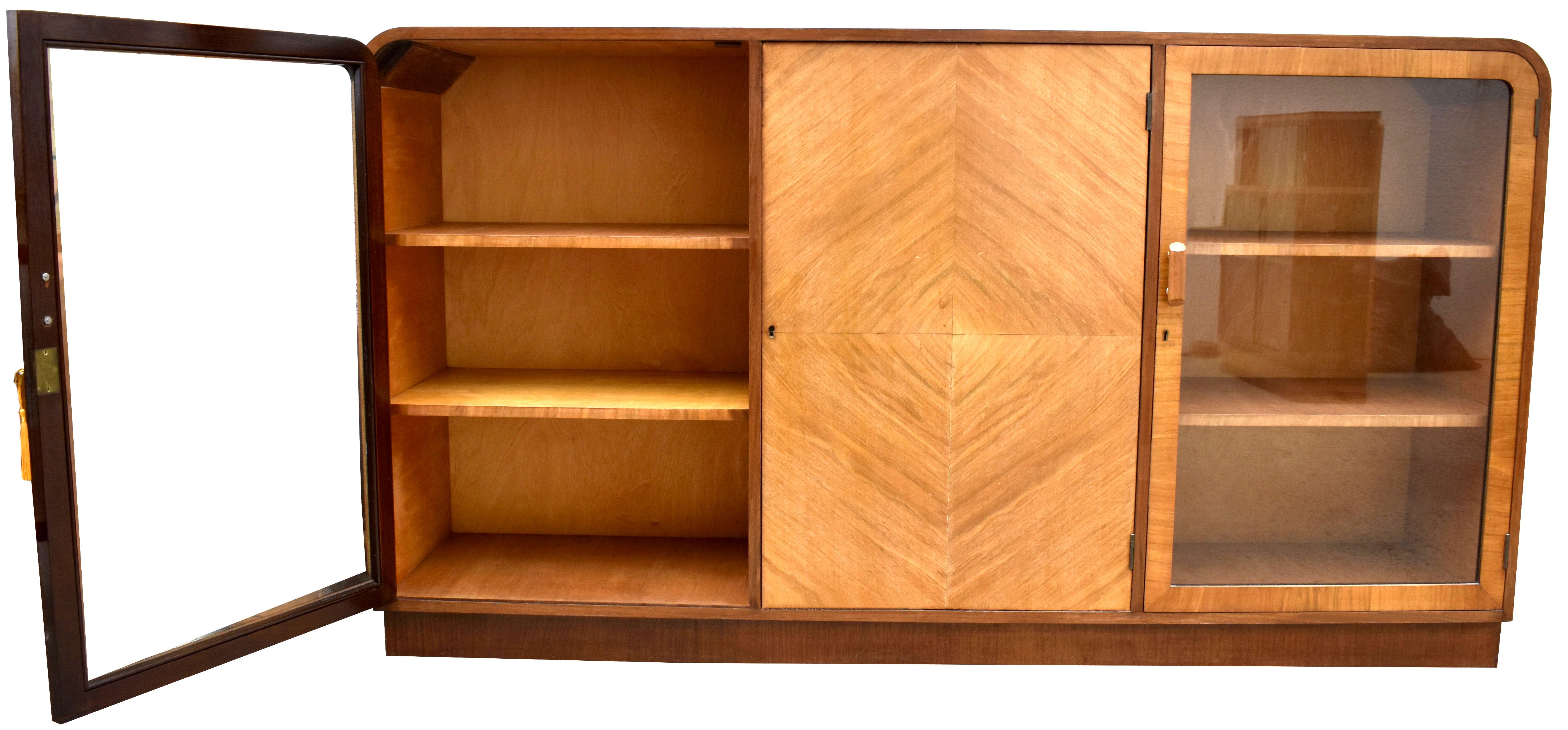 For your consideration is this fabulous floor standing round shouldered Art Deco glazed bookcase with a modernist slant. Dating to the 1930's and English made, this bookcase has beautiful blonde sycamore veneers with accented darker walnut veneered