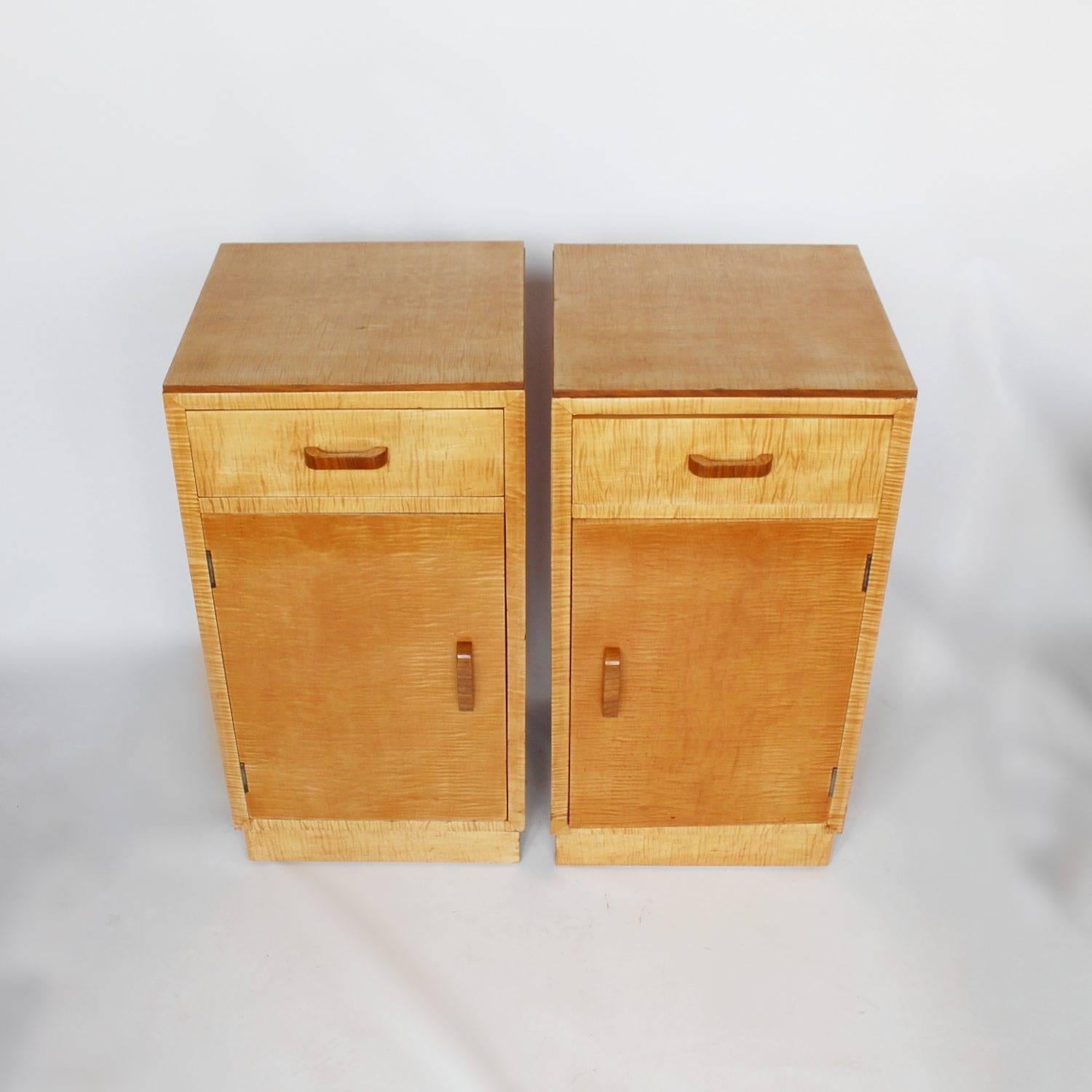 A pair of Art Deco bedside cabinets in satin birch with walnut banding and original wooden handles. Single drawer with shelved cabinet below.

 