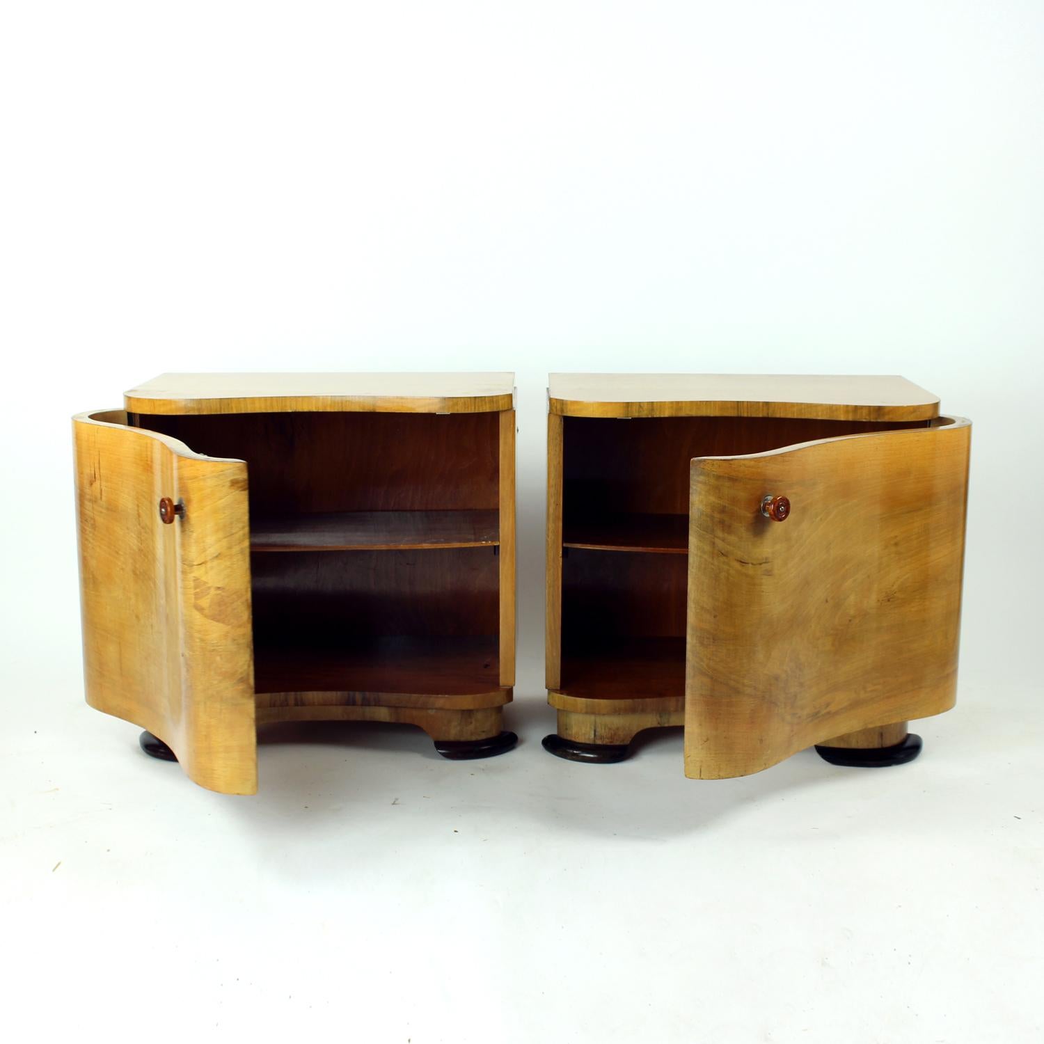 Cette rare paire de tables de chevet Art Deco vintage a été conçue par le célèbre designer tchèque Jindřich Halabala et fabriquée par UP Závody dans les années 1930. Avec leurs portes avant incurvées en placage de noyer, leurs poignées d'origine en