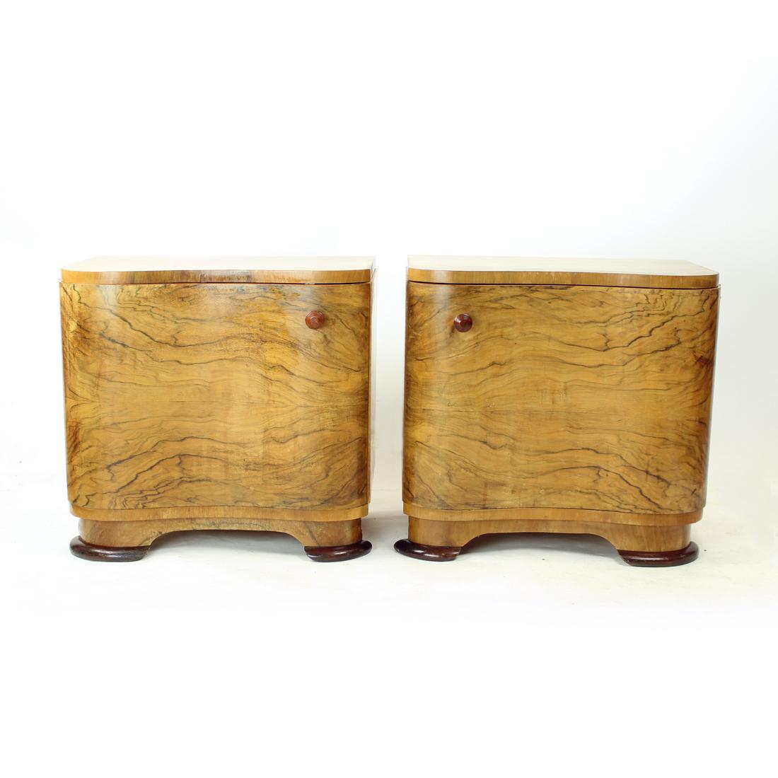 Set of two beautiful bedside tables from art deco era. Produced in Czechoslovakia in 1940s. They are trully unique in their design and use of veneer. The tables are made of oak wood with walnut veneer finish. The beautiful curvy design of the front