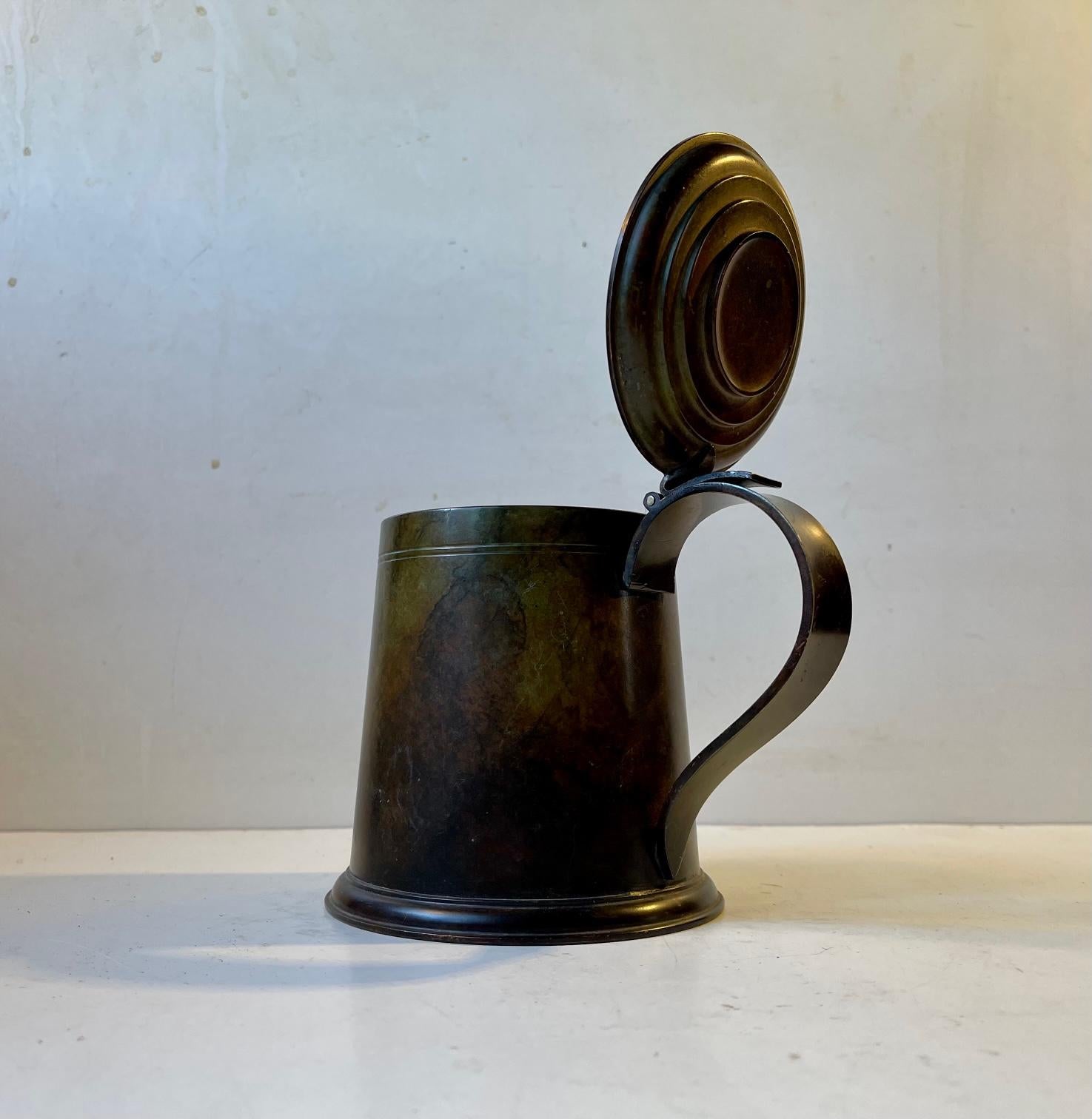 A stylish beer mug with flip-lid. Its made from verdigris patinated bronze. Probably made by Holger Fredericia - HF Ildfast in Denmark during the 1930s. It has no inscriptions and is wellkept. Measurements: H: 13.5 cm, Diameter: 11.5 cm. Capacity: