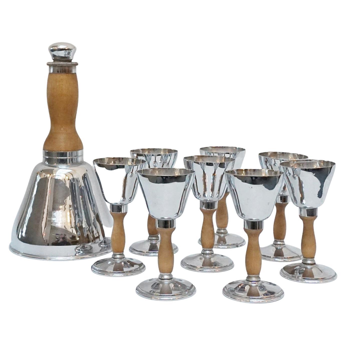 Art Deco cocktail shaker and eight cups. Shaker in the form of a bell. Metal and fruitwood. 

Dimensions: Shaker H 26.5cm D 14cm Cups H 13cm \

Origin: English 

Date: Circa 1930

Item Number: 222221.