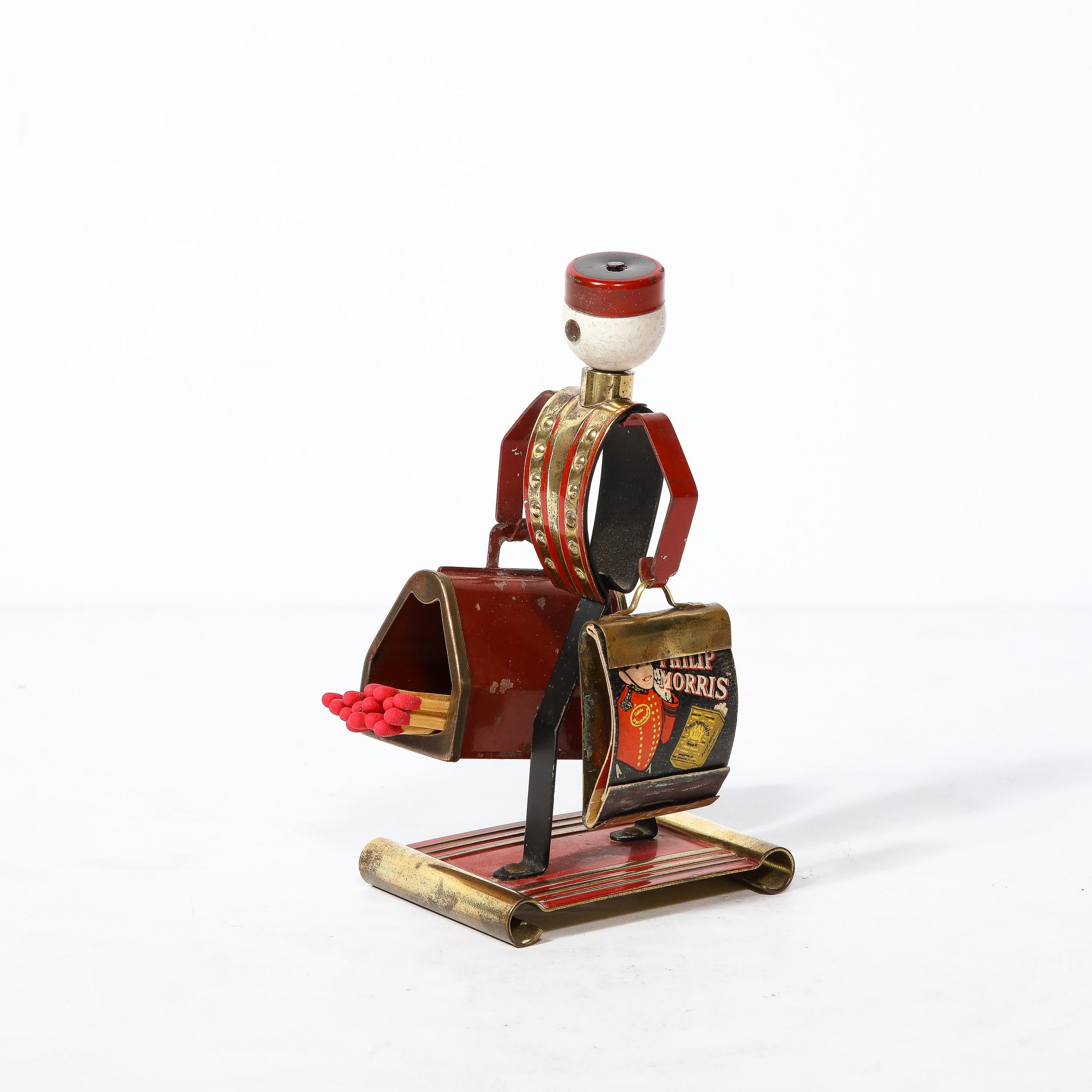 This Art Deco Cigarette/Matchbook Holder in Brass, Oak, and Enamel originates from the United States Circa 1930, manufactured by Chase for Philip Morris. Fabricated in painted brass and oak, this figurine is a rendering of an exceedingly popular