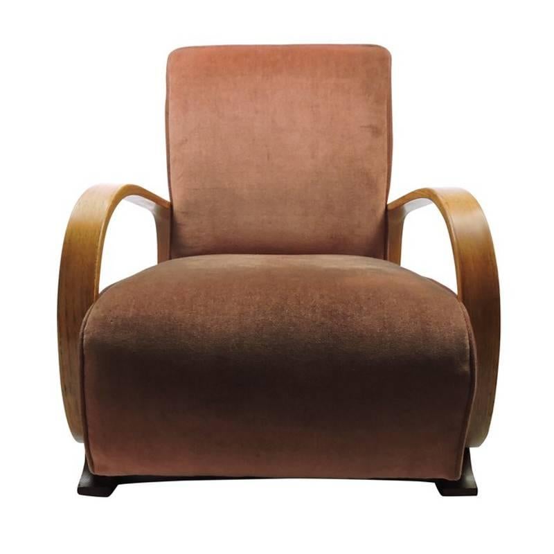 An Art Deco bentwood upholstered pink armchair made for Heals in the 1920s. The armchair features two large curved wooden arms and sits low to the floor.