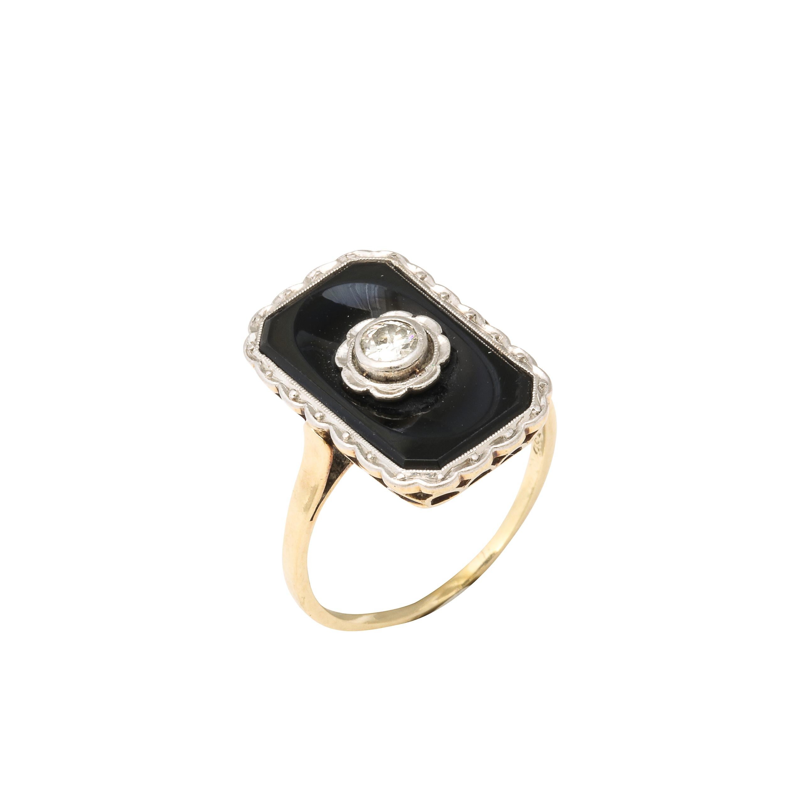 This Art Deco 14k bi -Color gold ring is set with a central rectangular cut black onyx displaying a single old European cut diamond set in 14 white gold in a stylized geometric design This ring could be worn to everything from a black tie event or