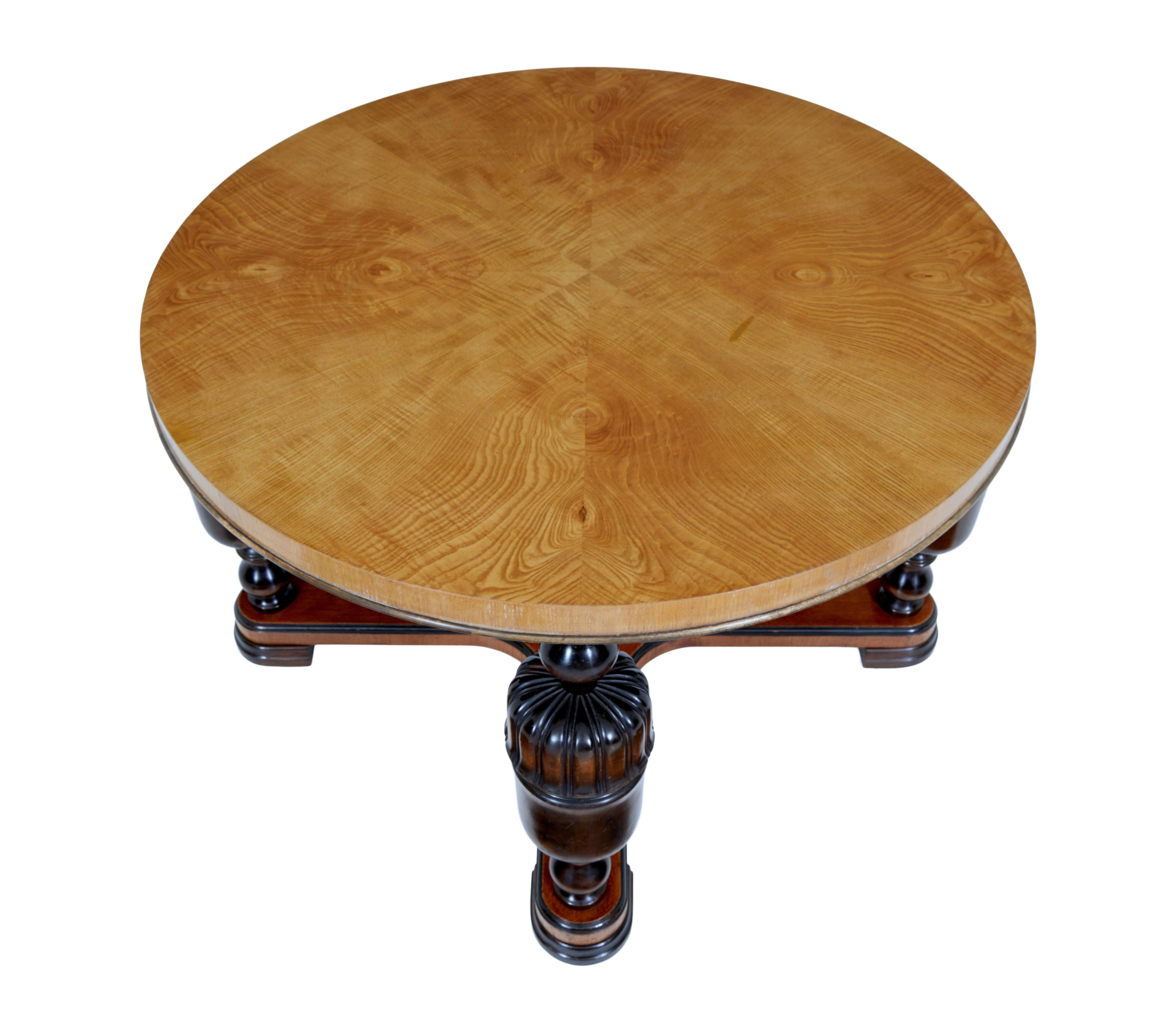 20th century Art Deco birch and elm coffee table, circa 1930.

Circular table top with matched elm veneers. Thick top is supported by 4 turned and fluted baluster legs united by an x-frame stretcher. Standing on ebonized flat hoof feet.

Minor