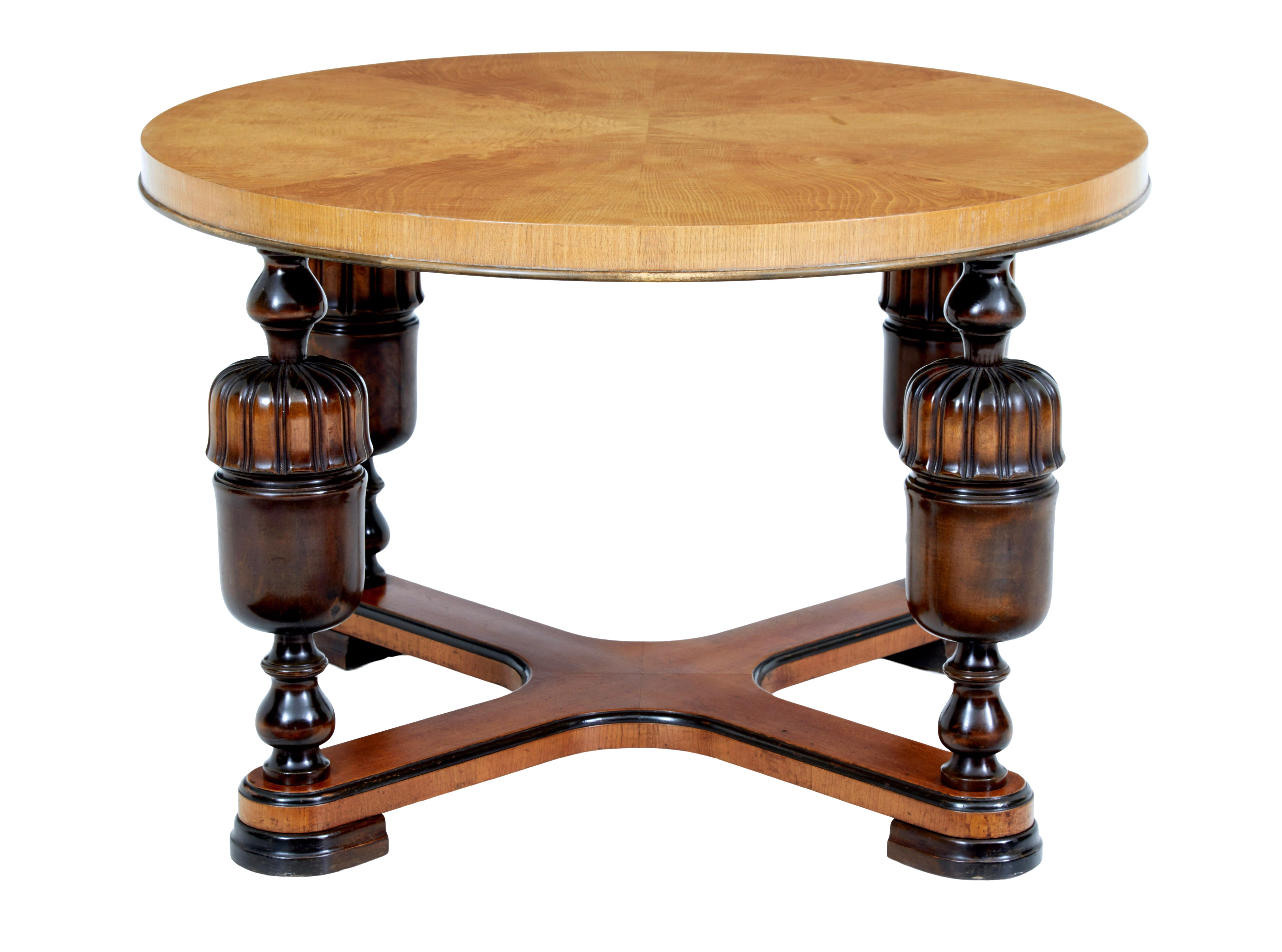 20th century art deco birch and elm coffee table, circa 1930.

Circular table top with matched elm veneers. Thick top is supported by 4 turned and fluted baluster legs united by an x-frame stretcher. Standing on ebonized flat hoof feet.

Minor