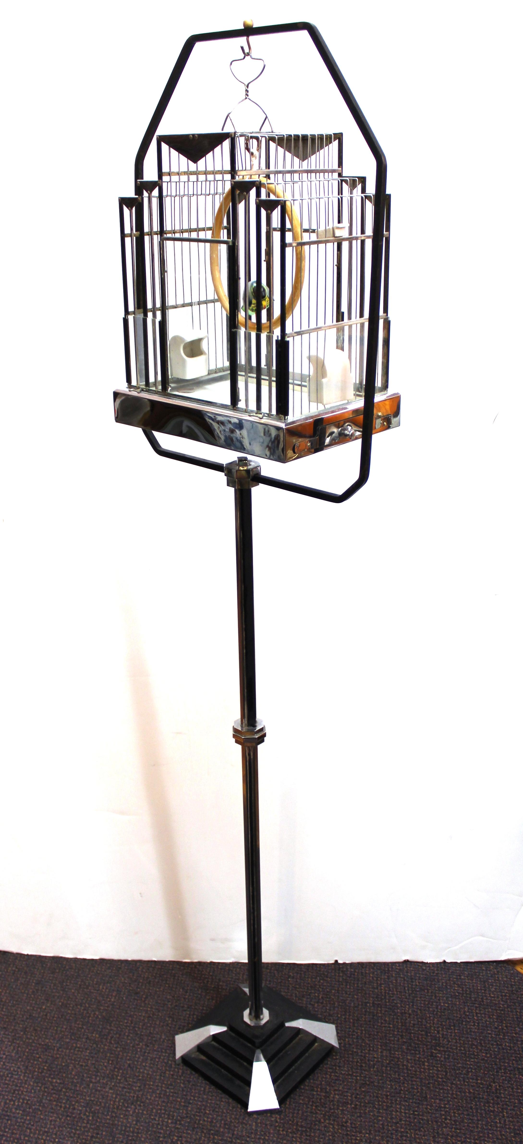 Art Deco period birdcage on stand, made in partly enameled black metal with accents and elements in chrome and etched glass pieces. The cage itself is shaped in the style of Hendryx birdcages and comes with a wooden bird sculpture. Two removable