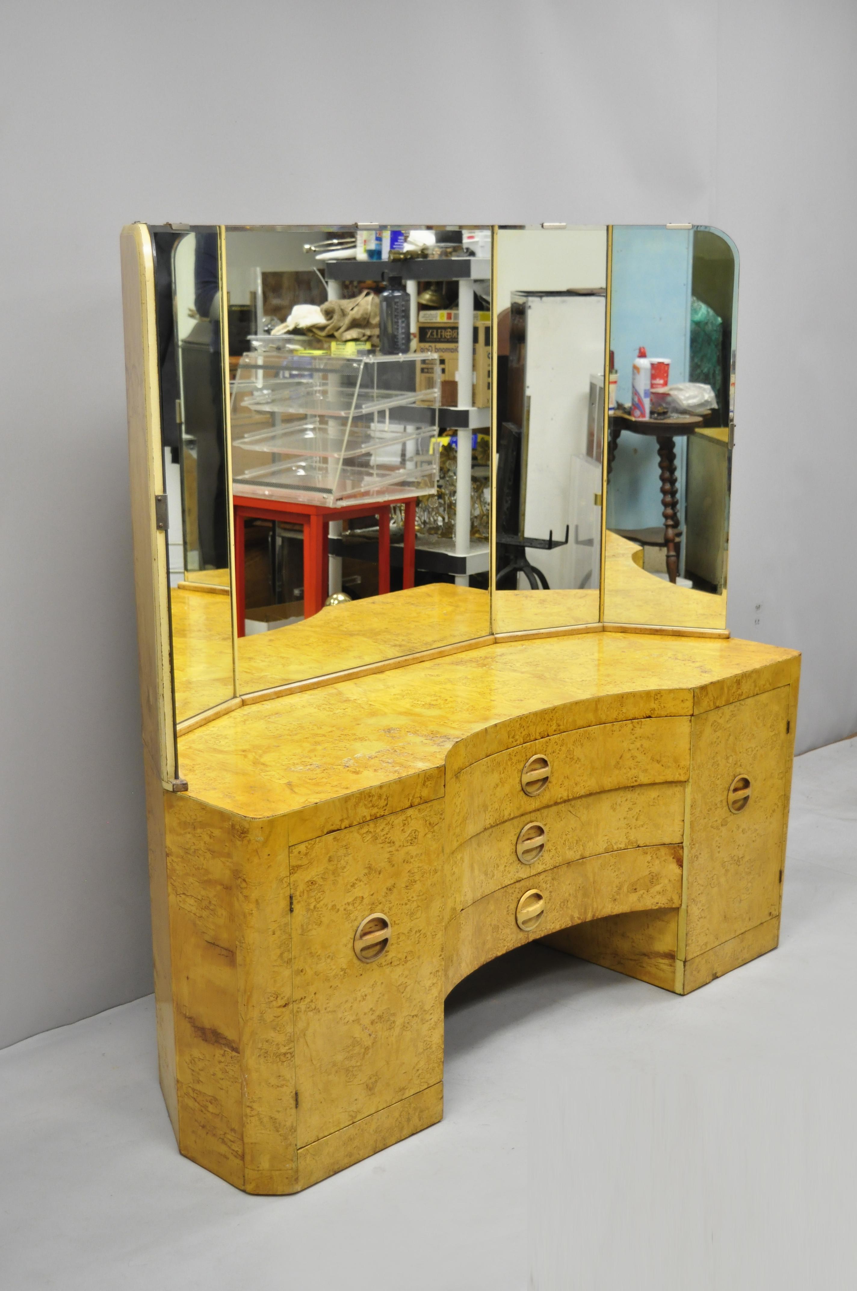 Antique Art Deco bird's-eye maple vanity with 5-panel mirror after Gilbert Rohde. Item features carved wood pulls, 5-panel vanity mirror, beautiful wood grain, 2 swing doors, and 3 dovetailed drawers; a very vintage item, circa 1940. Measurements: