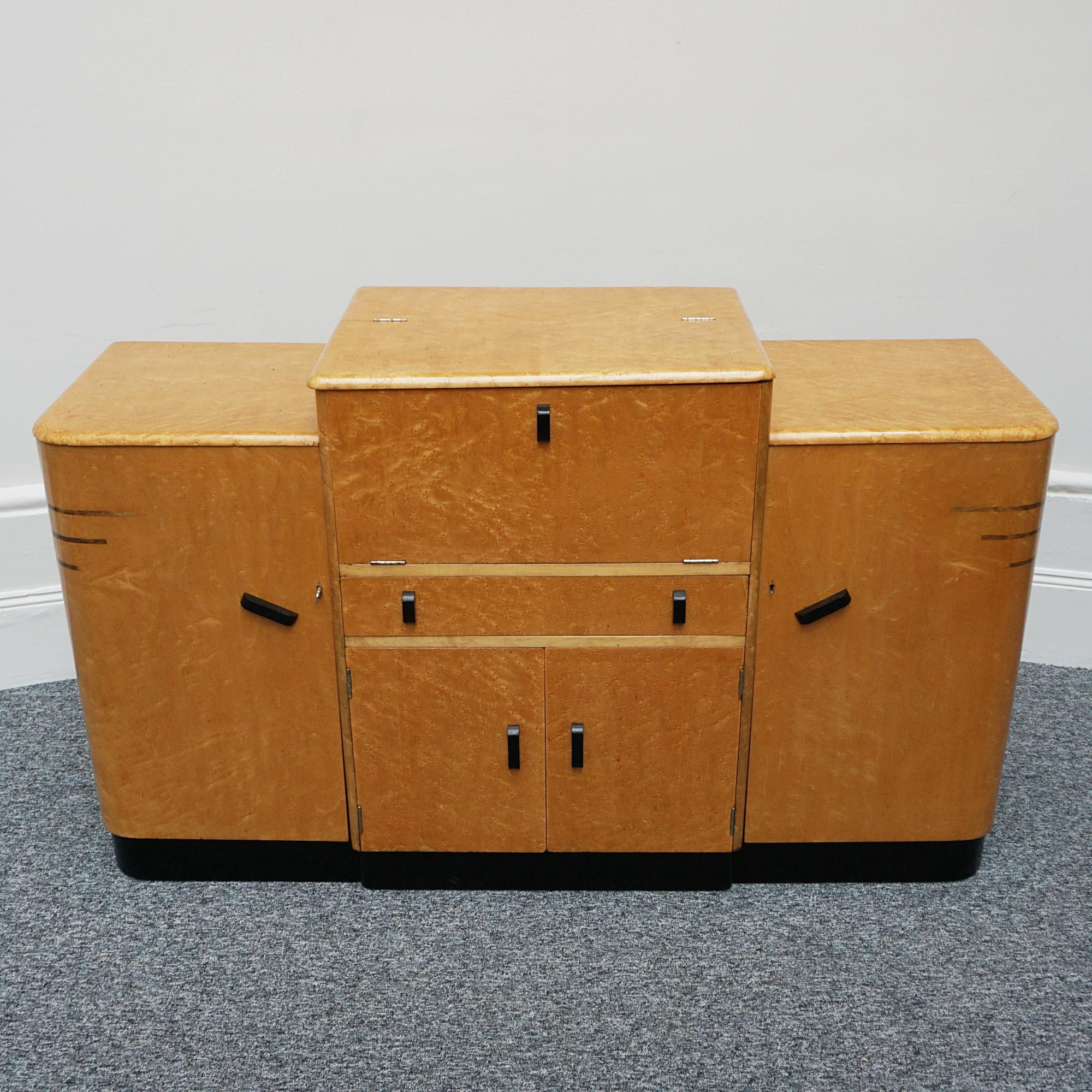 An Art Deco sideboard. Birdseye maple veneered with ebonised handles and banding. upper section opens to reveal a drinks cabinet with a central drawer below and cupboard sections to either side. 

Dimensions: H (to centre) 93cm (to sides) H 83cm W
