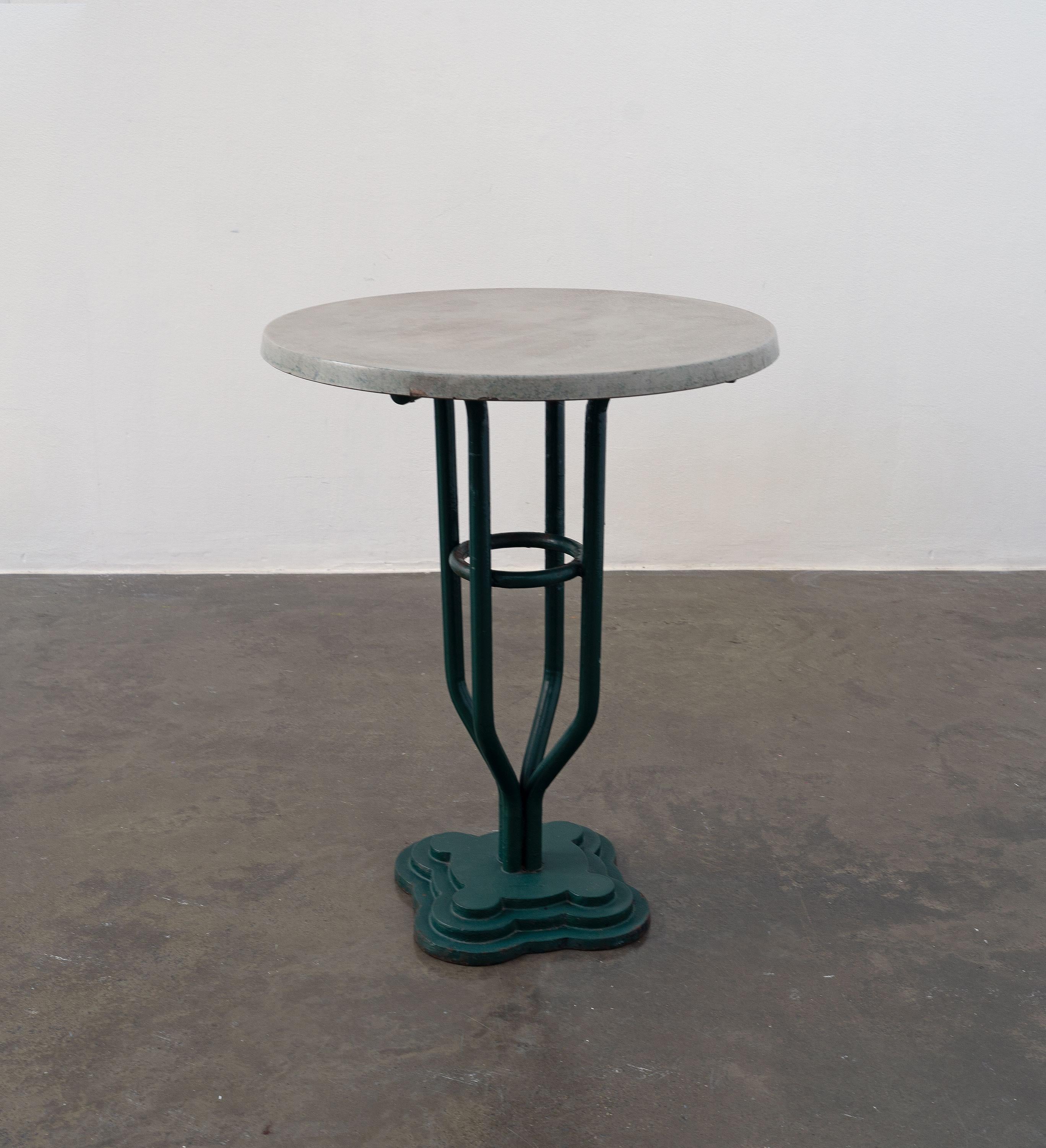 A charming 1930's Portuguese bistro table featuring a cast iron base with four columns that bend to meet at a graduated quadrifoglio-like base. The table top is zinc on wood. 

Dimensions (cm, approx):
Height: 80
Diameter: 60

In fair vintage