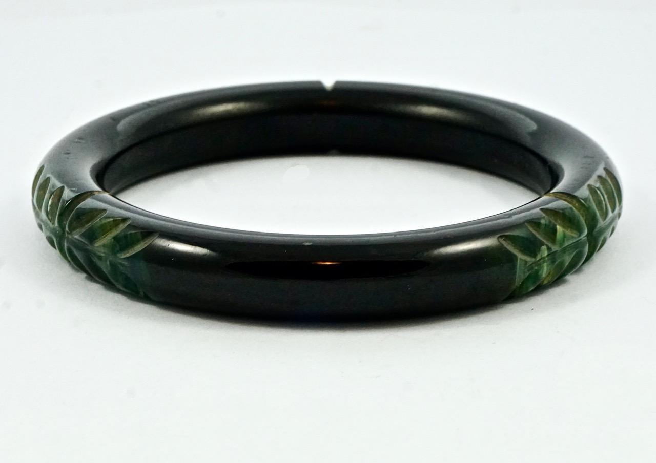 Wonderful Art Deco black Bakelite bangle with marbled green leaves carving. Inside diameter 6.4cm / 2.5 inches by width 1.1cm / .4 inch. The bangle is in very good condition, with some scratching.

This is a beautiful vintage carved Bakelite bangle