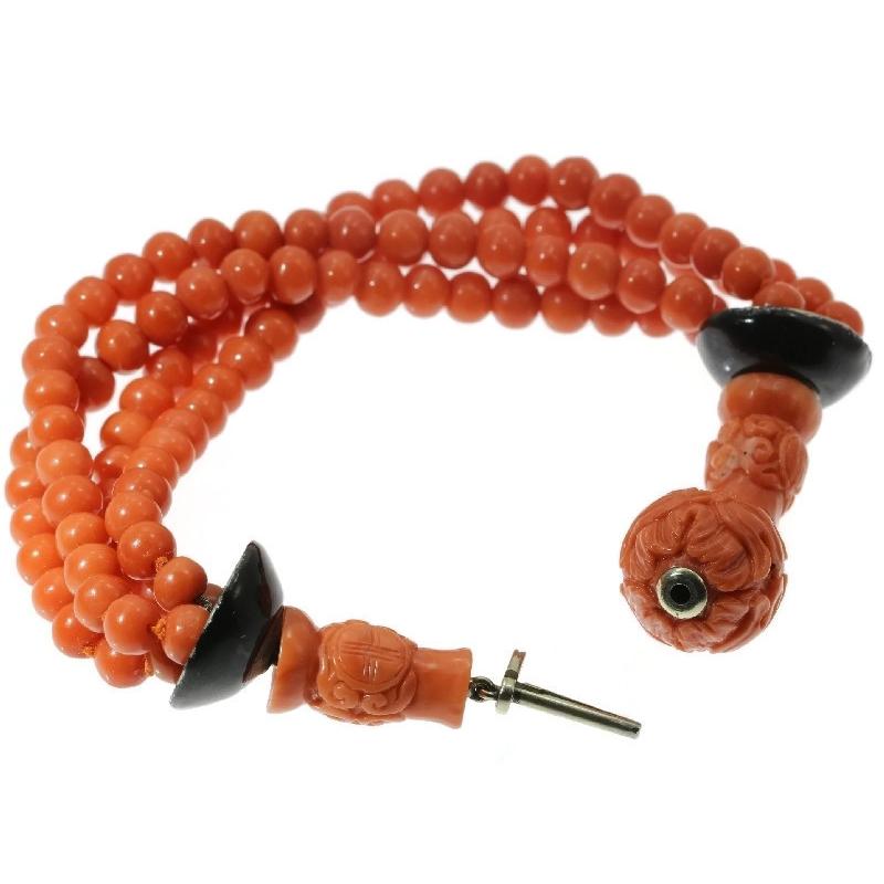 This Art Deco bracelet ascends from customary antique jewellery to the level of applied arts due to its rare combination in craftsmanship of goldsmithed 18K yellow gold, of delicately engraved coral beads and of a black enamelled finish. Four coral