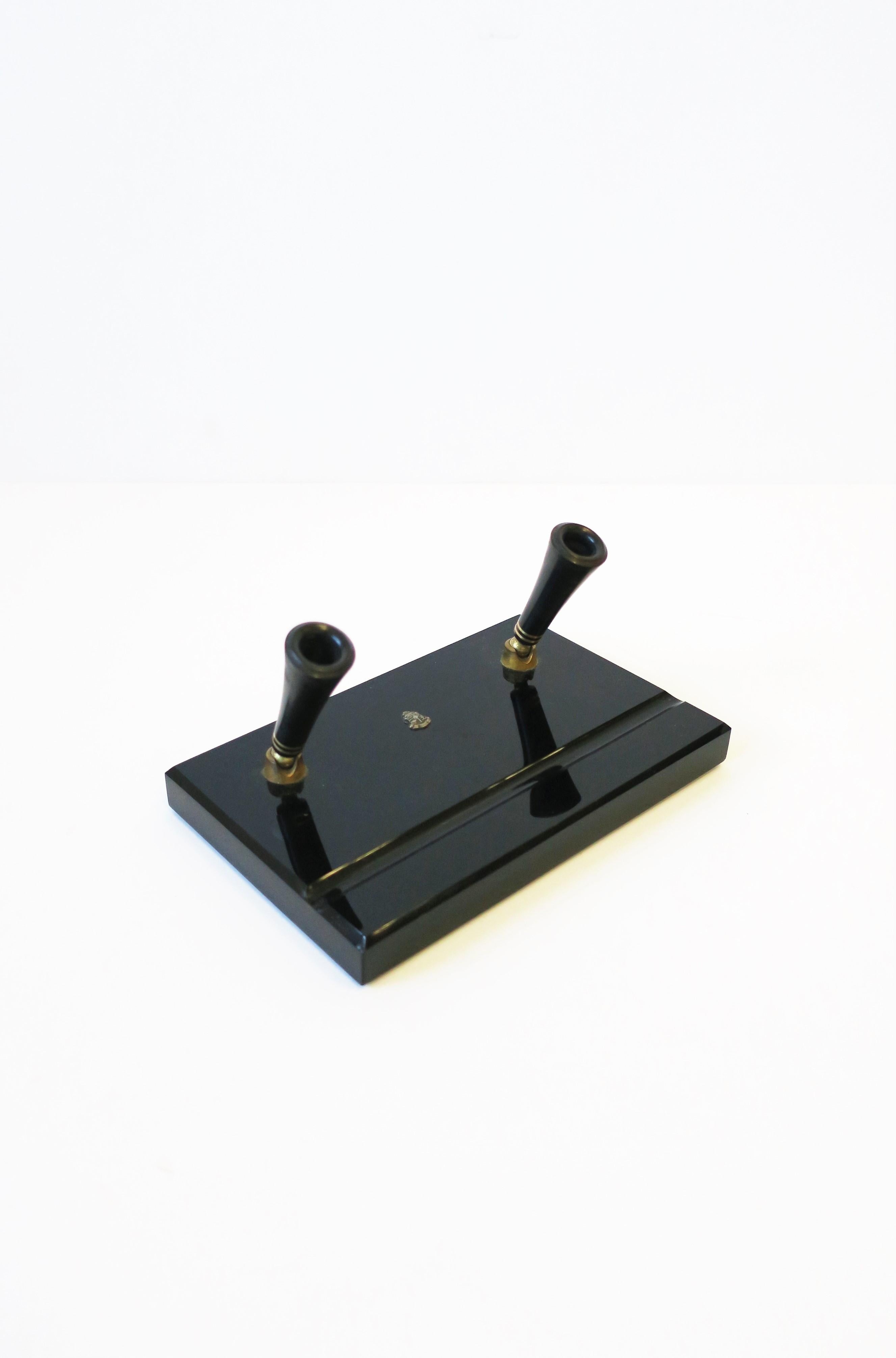 An Art Deco period black glass and brass desk pen holder with crest, circa 20th century. Piece holds standard size pen. Crest at front center is a scull w/cross-bones. 

Other items in images also available, search 1stdibs ID#s: 
Malachite Dish