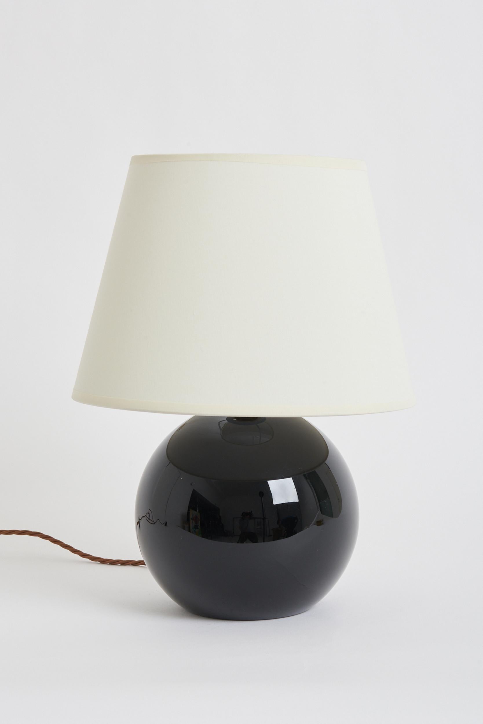 An Art Deco black opaline glass table lamp by Jacques Adnet (1900-1984).
France, circa 1930.
Measures: With the shade: 40 cm high by 30.5 cm diameter 
Lamp base only: 26 cm high by 17 cm diameter.