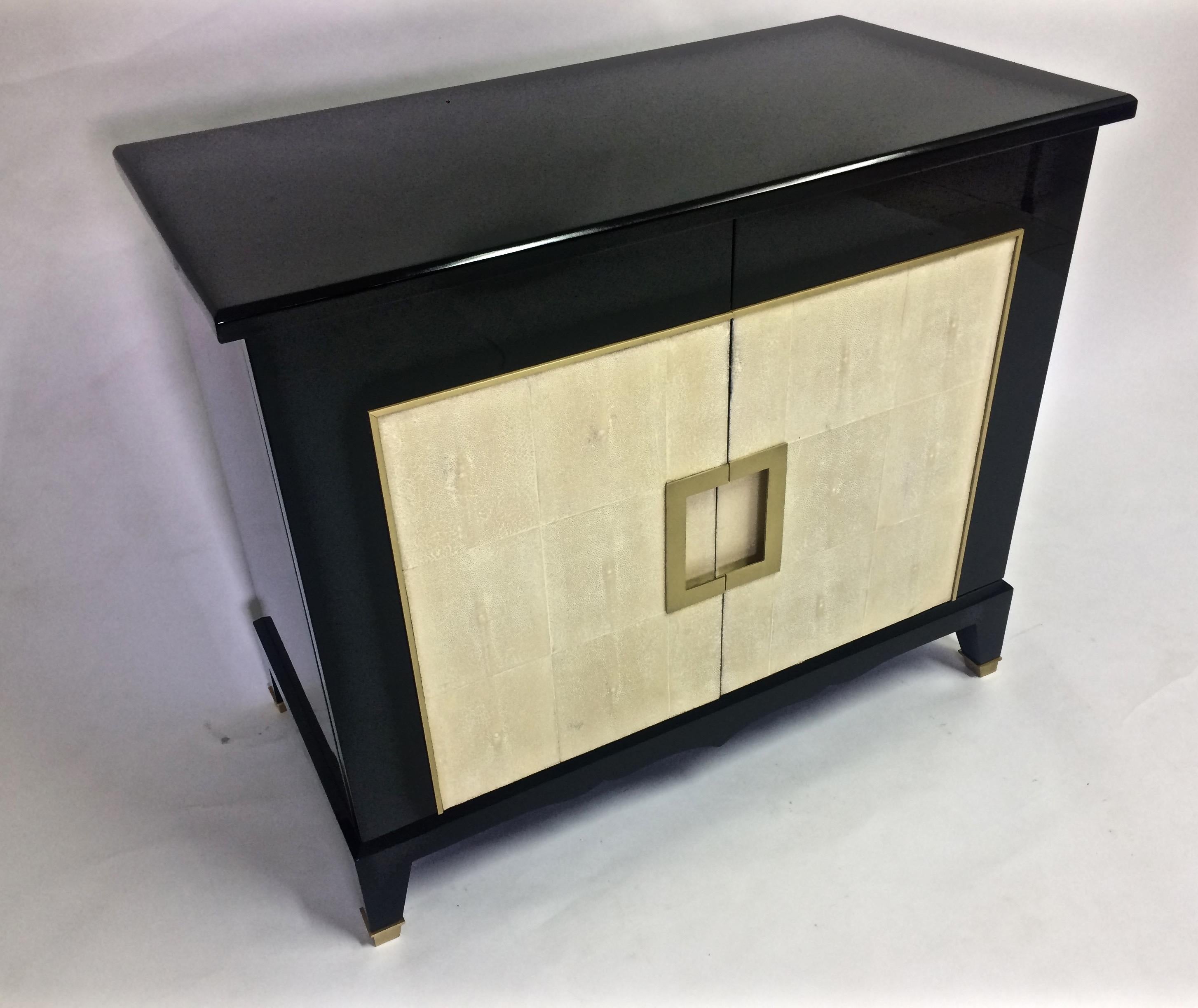 Art Deco black lacquer and shagreen cabinet, the rectangular polished black lacquer top over a cabinet with two doors veneered with natural cream colored shagreen and brass inlaid molding, all opening to an interior with one adjustable shelf, raised