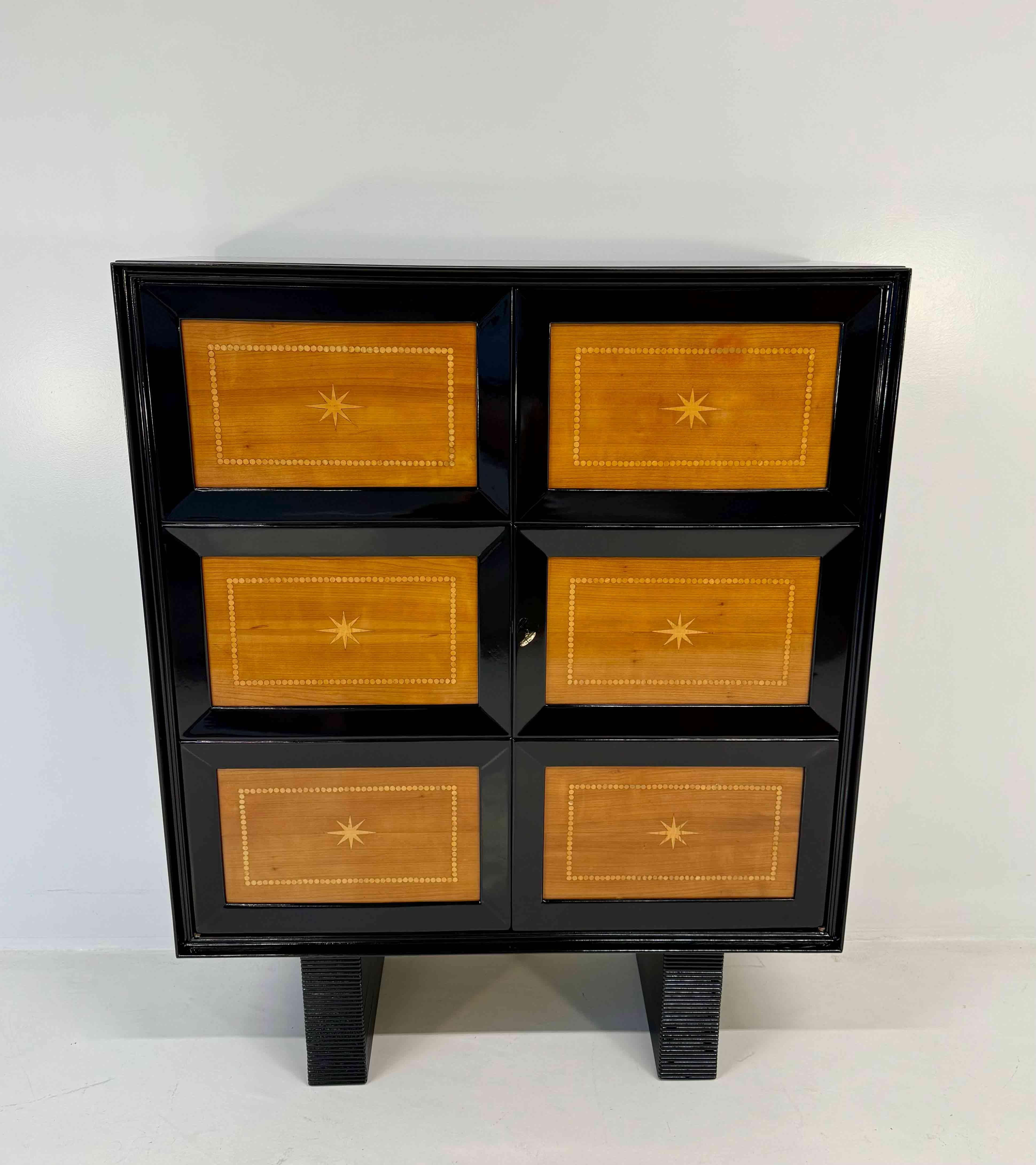 Elegante armario Art Déco fabricado en Italia en la década de 1950 y atribuido a Osvaldo Borsani.
La estructura está lacada en negro con incrustaciones de madera de cerezo y arce que acentúan su ritmo geométrico y el contraste de materiales.
Las
