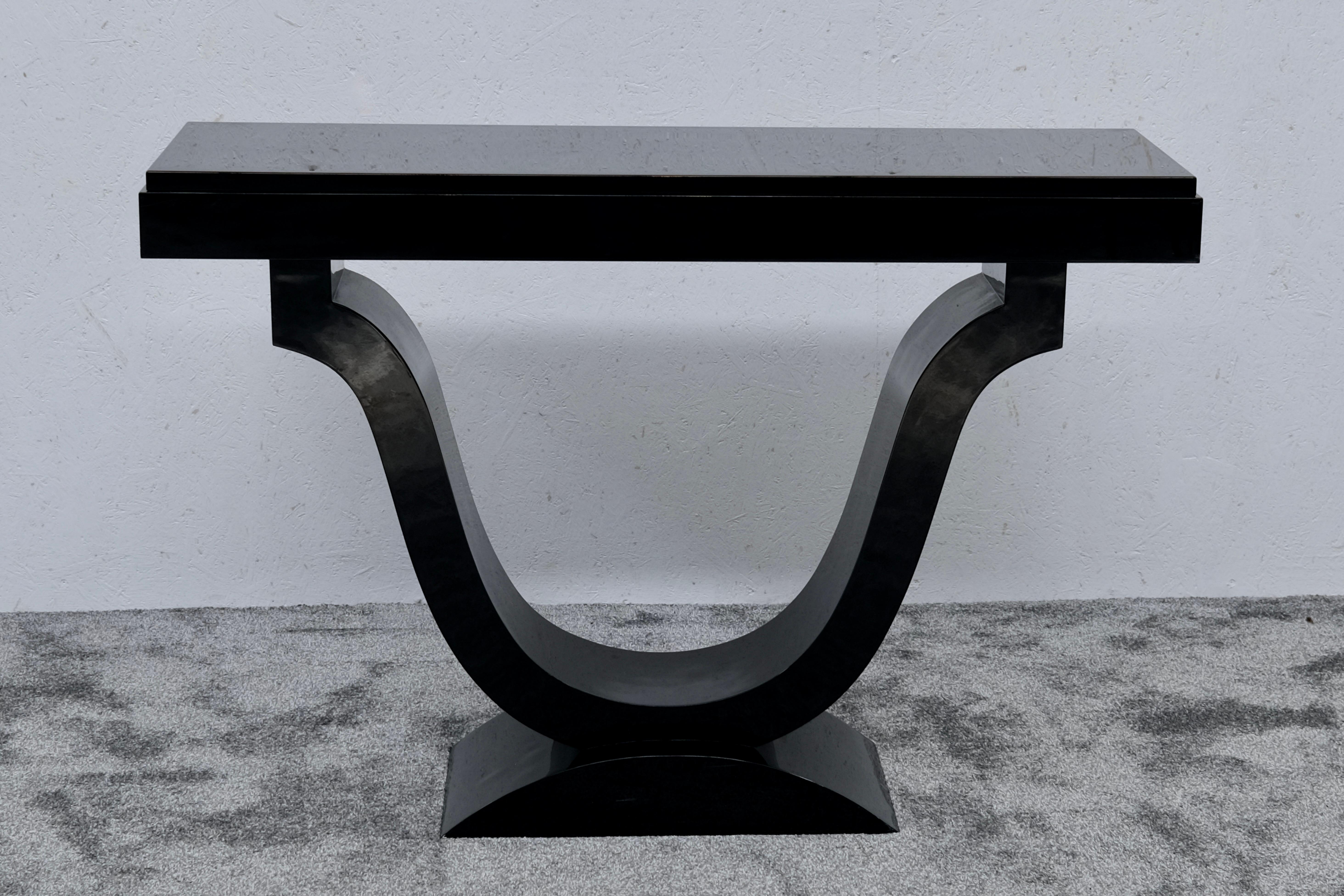 This Art Deco console in deep black lacquer features a sculptural tulip-shaped center support rising from an arched base — a refined expression of 1930s French design. The top is set on a clean, rectangular frame, while the sweeping curve beneath