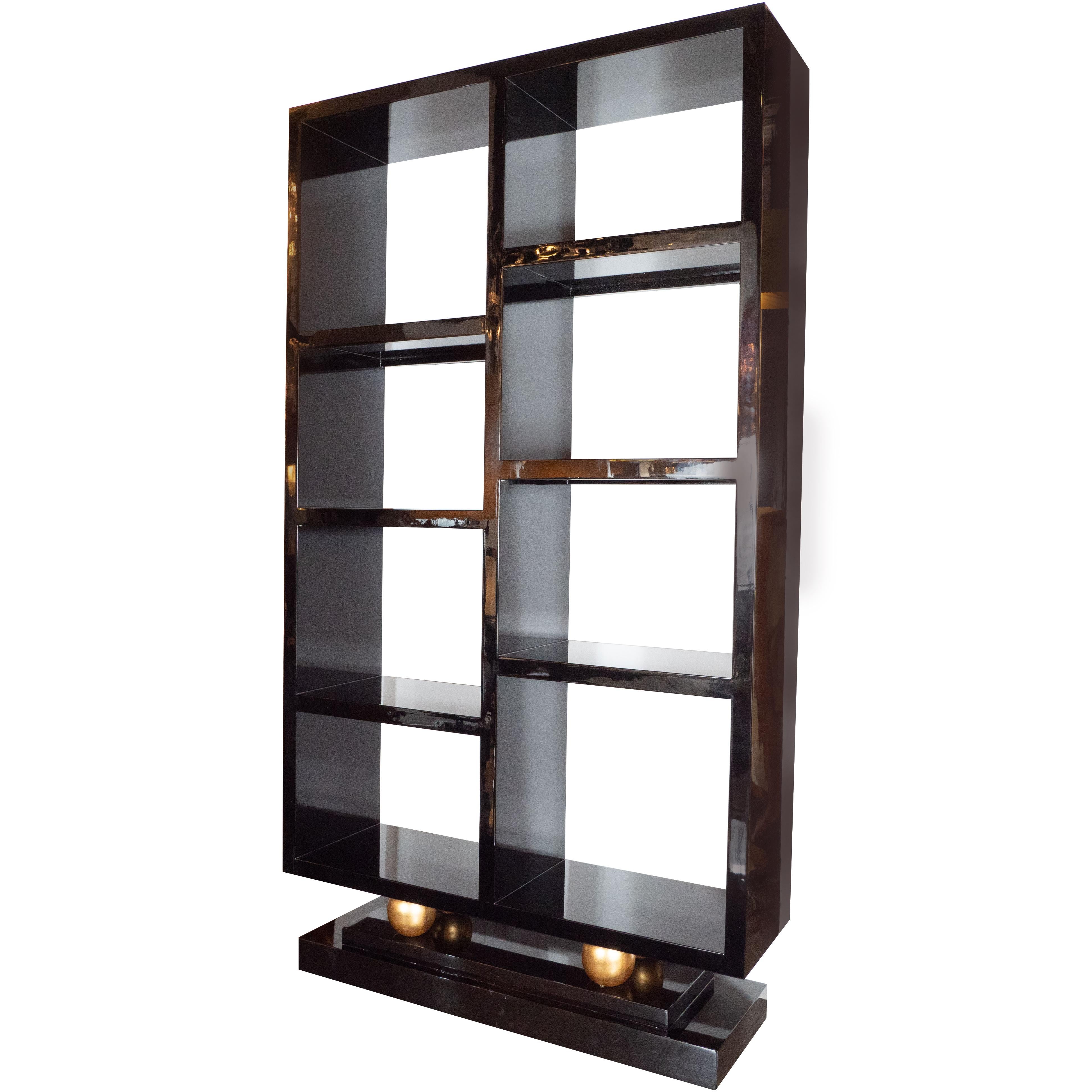 This magnificent Art Deco style étagère or bookshelf was realized in the United States, circa 1935. It features a rectangular body with eight shelves and a skyscraper style base all executed in lustrous black lacquer. Two orbital embellishments,
