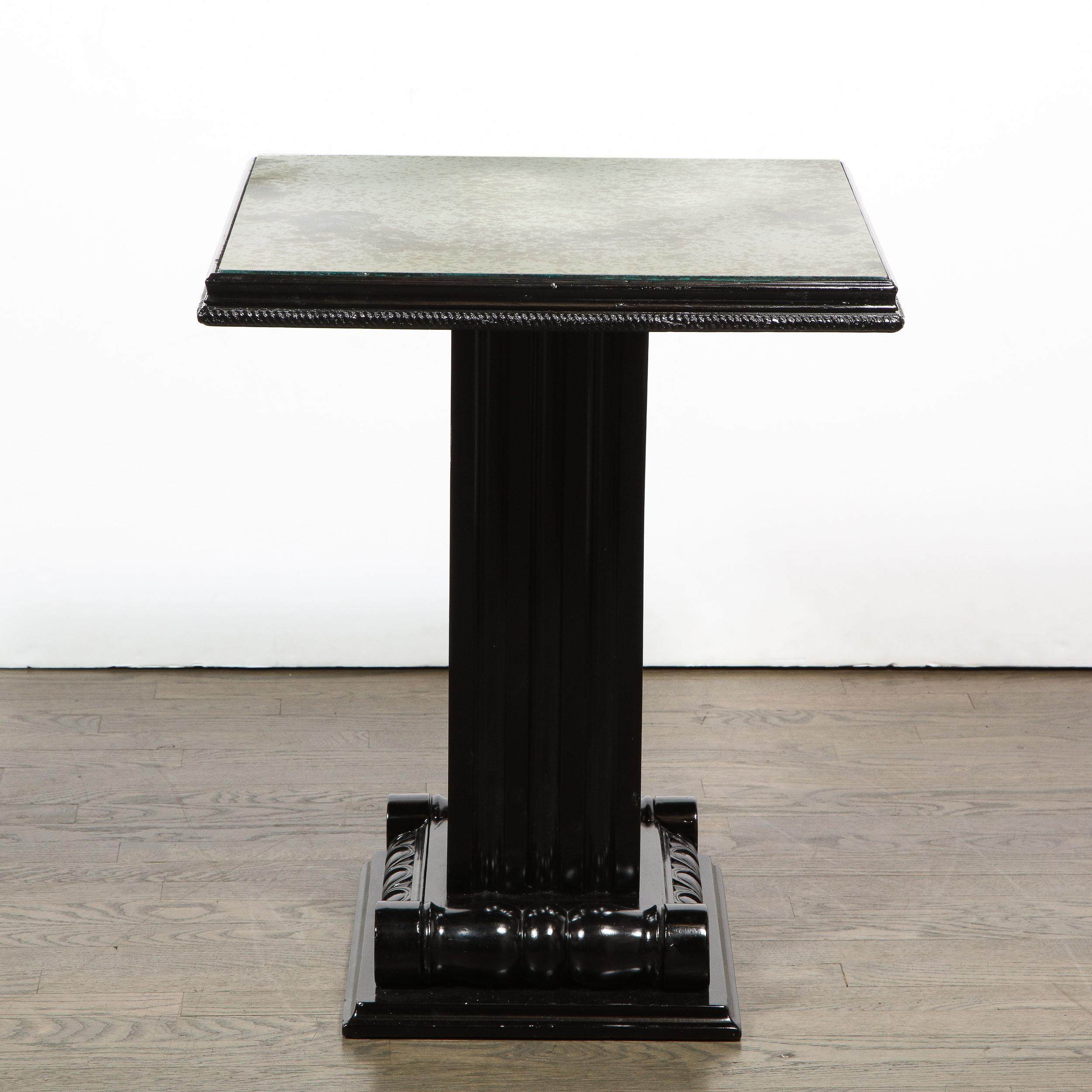 This stunning and graphic Art Deco Hollywood occasional table was realized in the United States, circa 1940 by Grosfeld House. It features a stylized acanthus leaf base that ascends into a channeled body. A square antiqued mirror- with a lovely top-