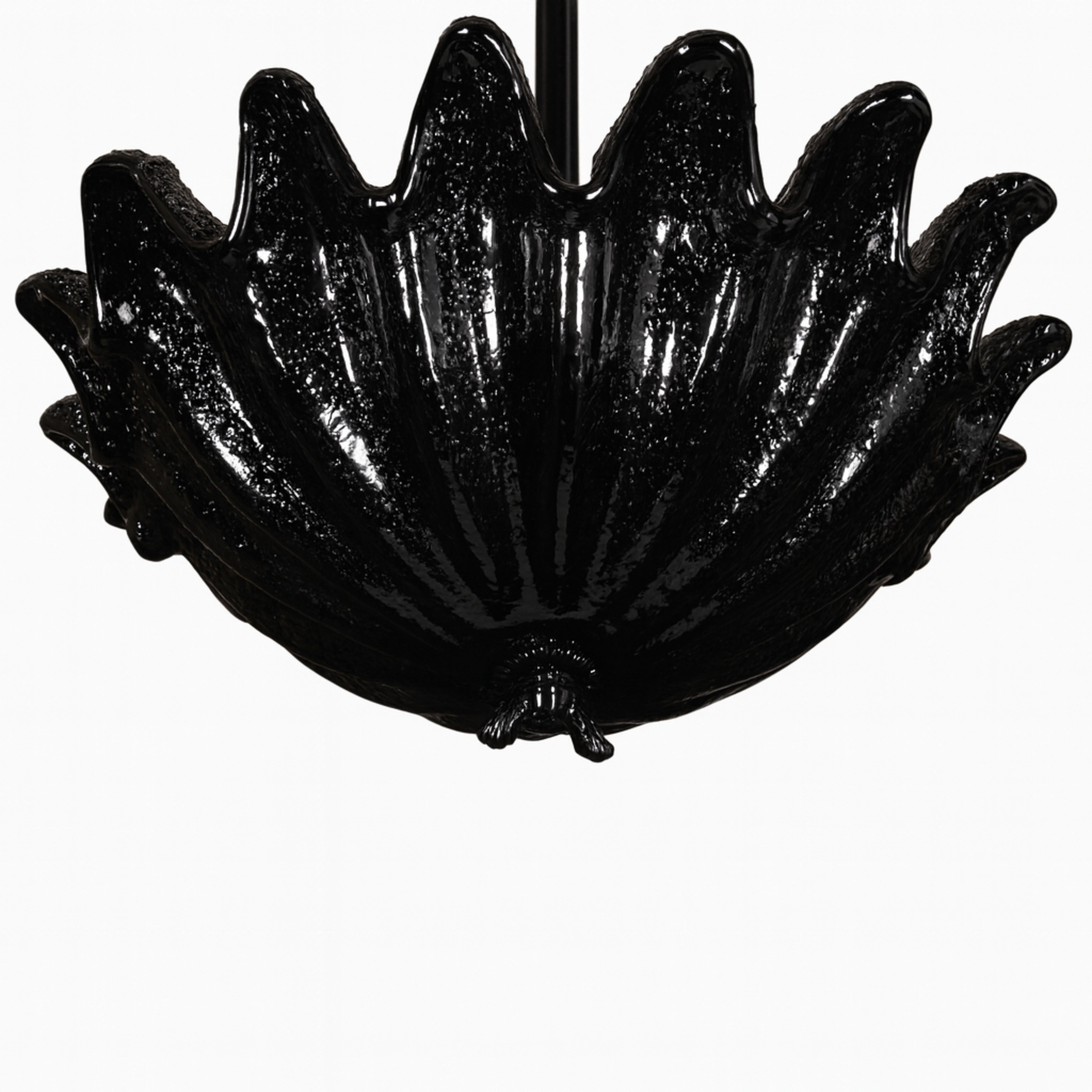 Cette lampe suspendue Art Deco, laquée noir, est dotée d'un abat-jour translucide en verre de Murano surmonté d'un dôme en forme de feuille.
Le luminaire central est gracieusement suspendu à une élégante lampe à incandescence.  Ce qui lui confère
