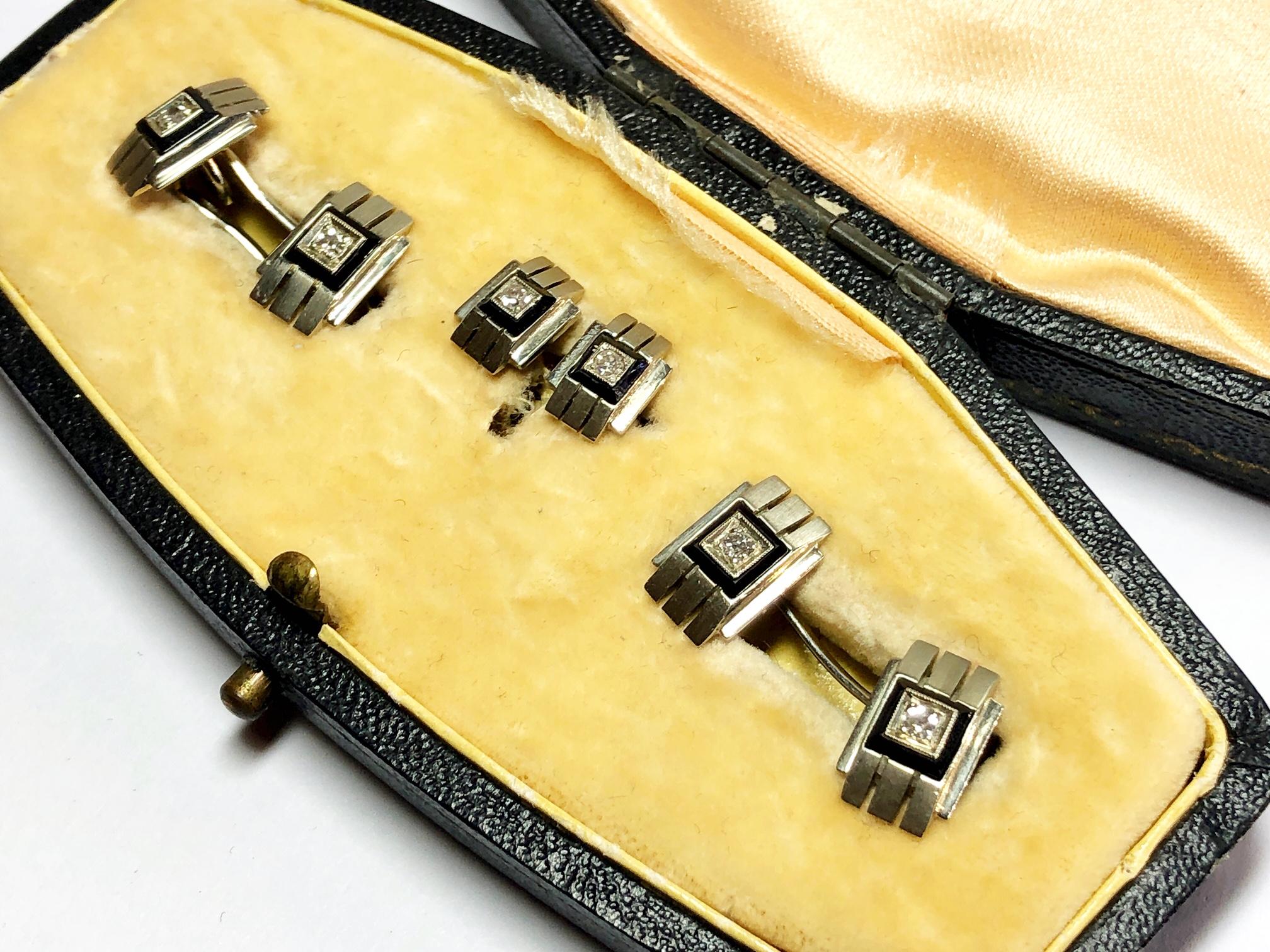 An Art Deco gentlemen's dress-set, comprising of a pair of cufflinks and two studs, each with a central old cut diamond, in a square black onyx border on an 18ct white gold detailed panel measuring an estimated 13 x 8mm, stud measuring 11 x 6mm,