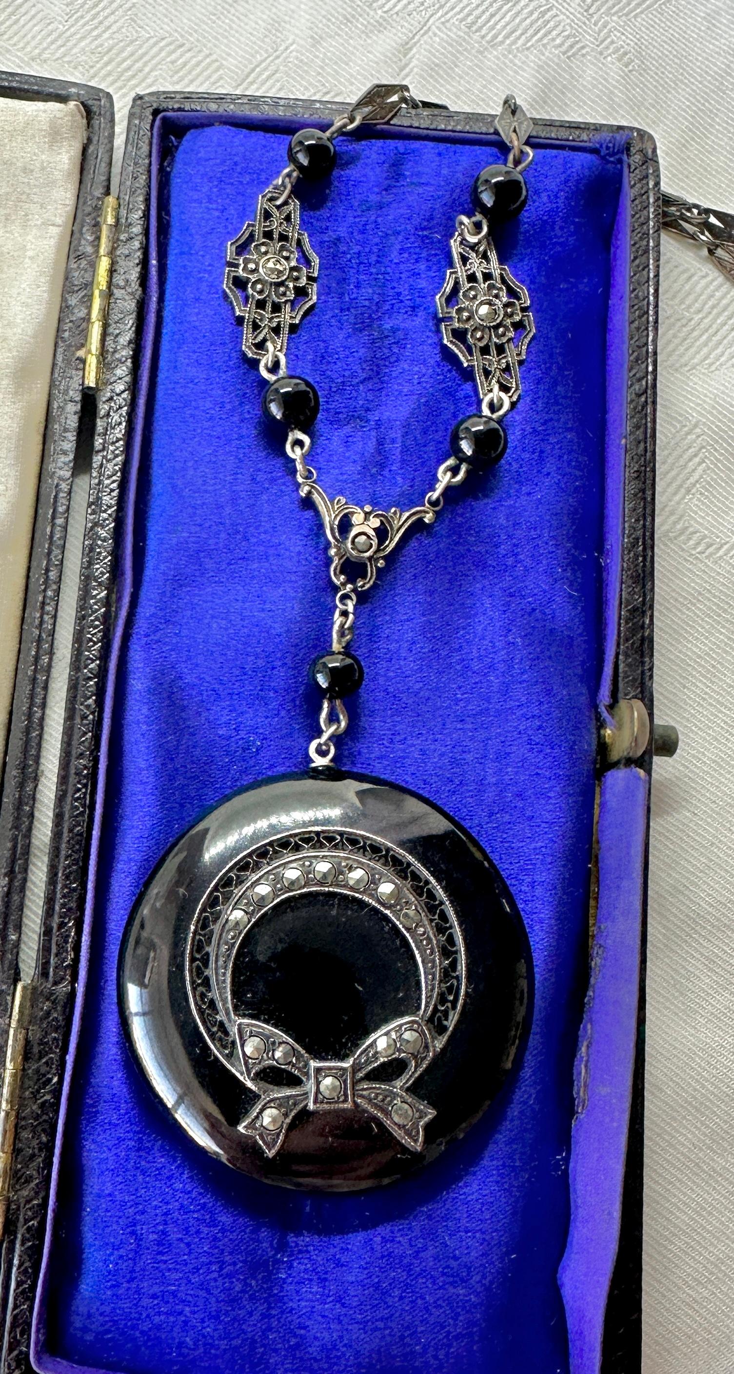 THIS IS A STUNNING ORIGINAL ANTIQUE ART DECO BLACK ONYX MARCASITE NECKLACE OF THE FINEST QUALITY.  THE PENDANT NECKLACE HAS A MAGNIFICENT ROUND BLACK ONYX PENDANT SET WITH A STERLING SILVER BOW MOTIF DESIGN WITH MARCASITE GEMS.  THE PENDANT HANGS