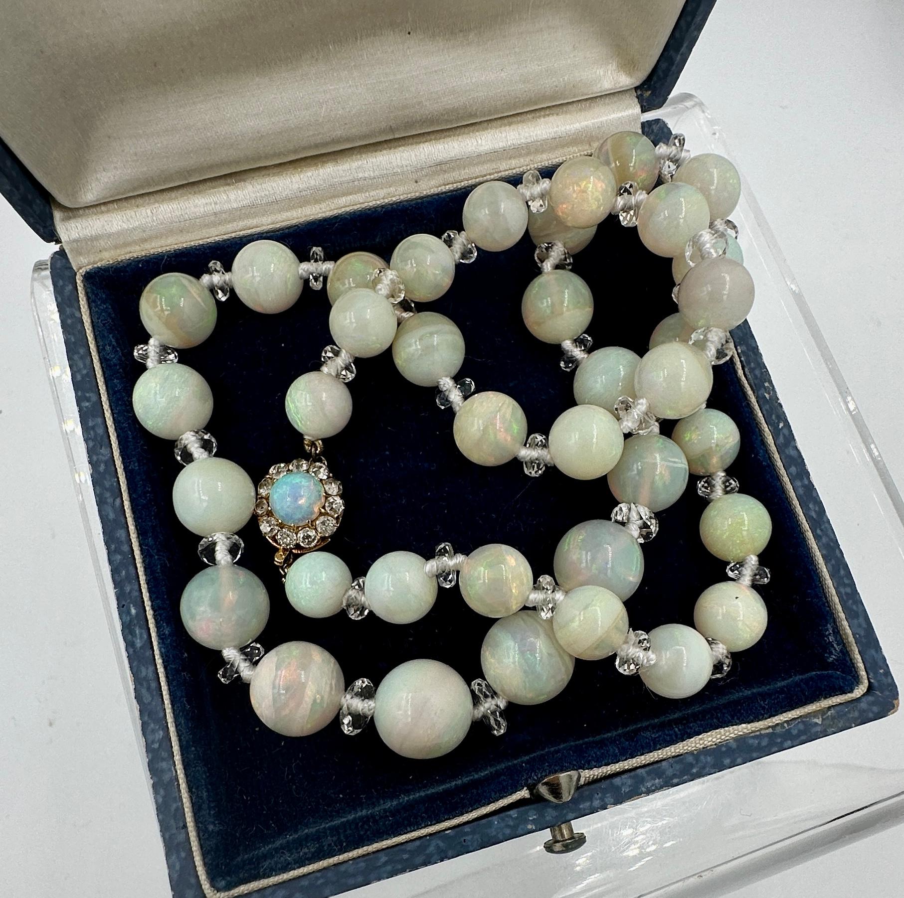 INDULGE IN THIS RARE AND MAGNIFICENT ANTIQUE ART DECO OPAL AND ROCK CRYSTAL BEAD NECKLACE WITH A SPECTACULAR BLACK OPAL AND ROSE CUT DIAMOND CLASP IN 14 KARAT GOLD.  THE EXTRAORDINARY JEWEL HAS THE MOST STUNNING NATURAL MINED ROUND OPAL BEADS THAT