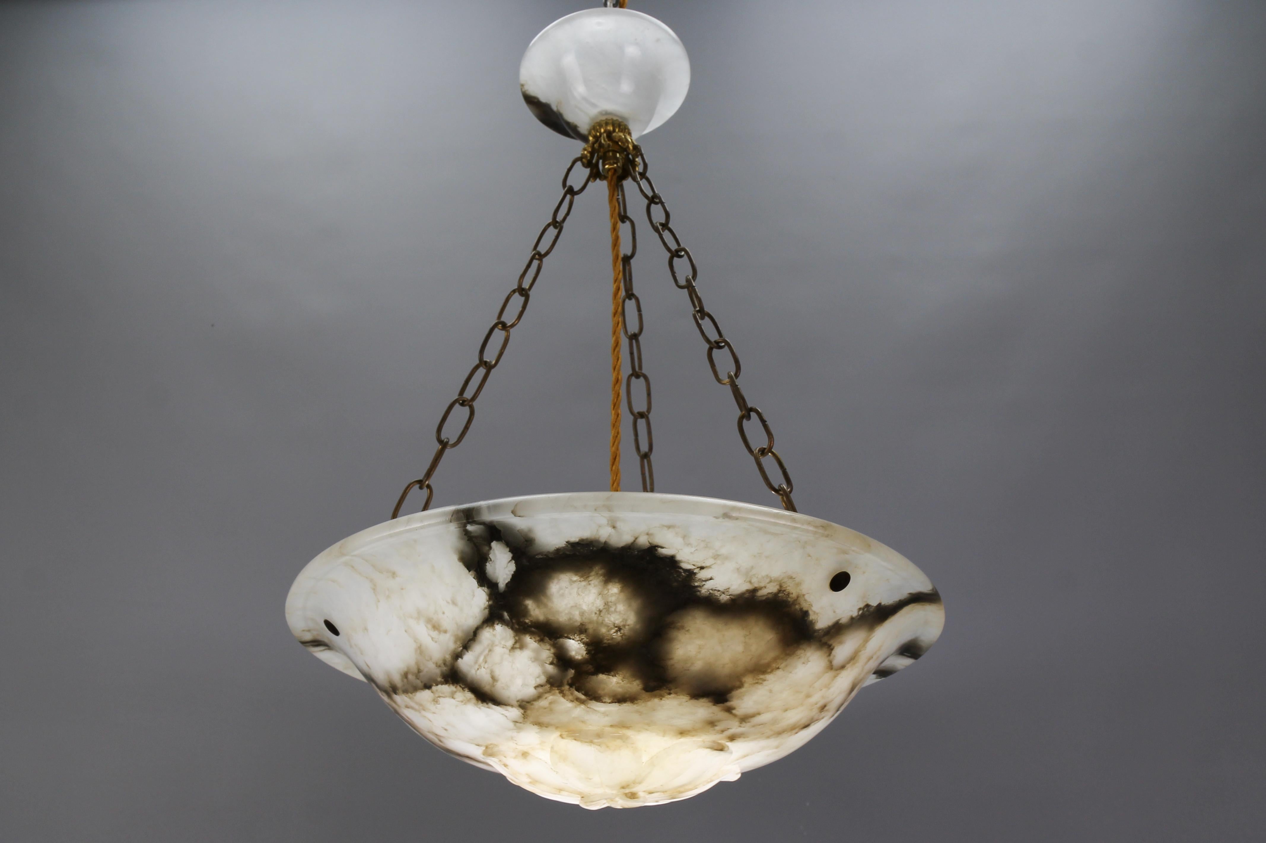 Antique French Art Deco black veined cloudy or dark white alabaster pendant light fixture.
A superb alabaster pendant ceiling light fixture from circa 1920. This richly veined and beautifully carved alabaster bowl is suspended by three chains and an