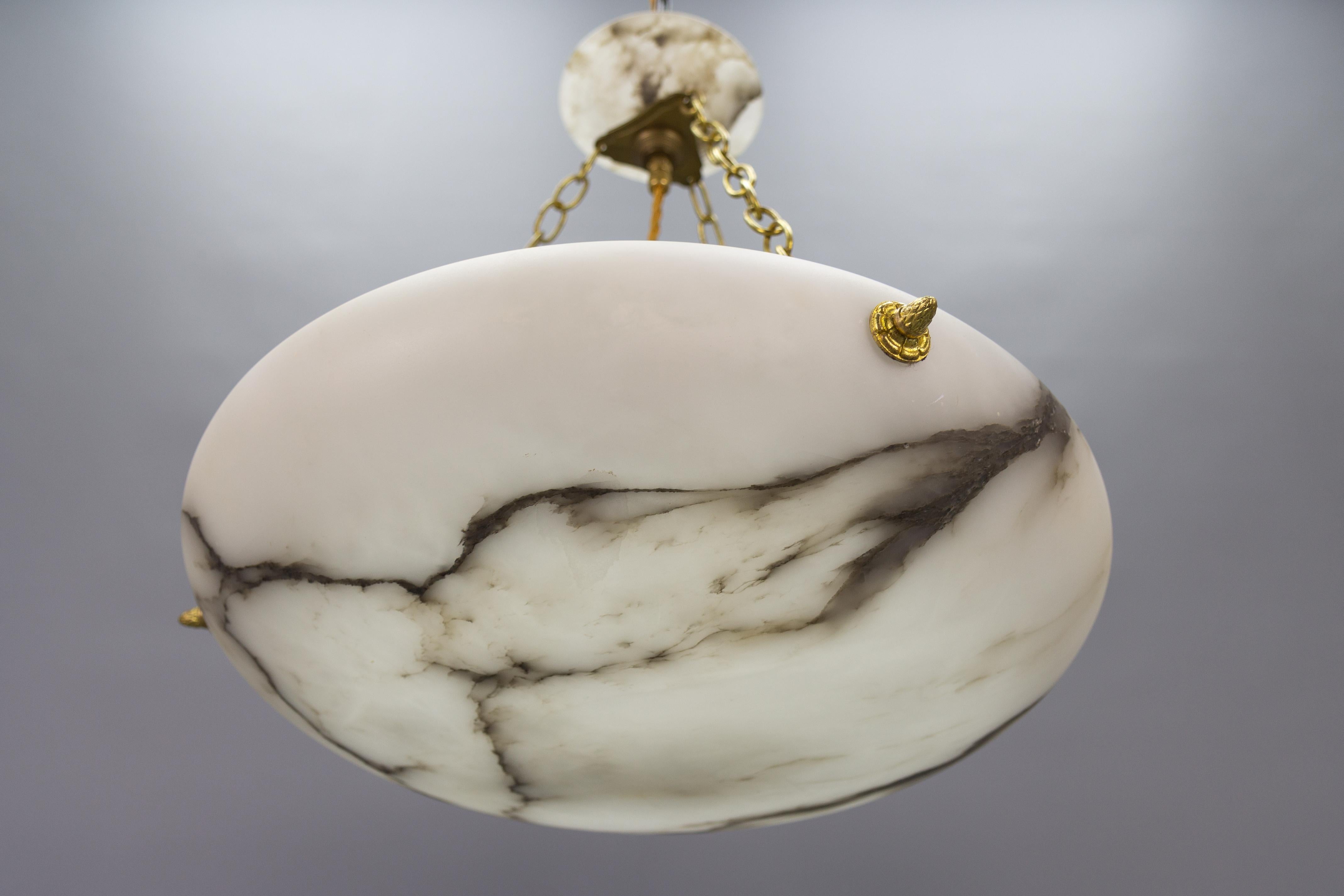 A French Art Deco period black veined white alabaster pendant light fixture.
A wonderful alabaster pendant ceiling light fixture from circa the 1920s. Beautifully veined and masterfully carved ufo-shaped white alabaster bowl suspended by three