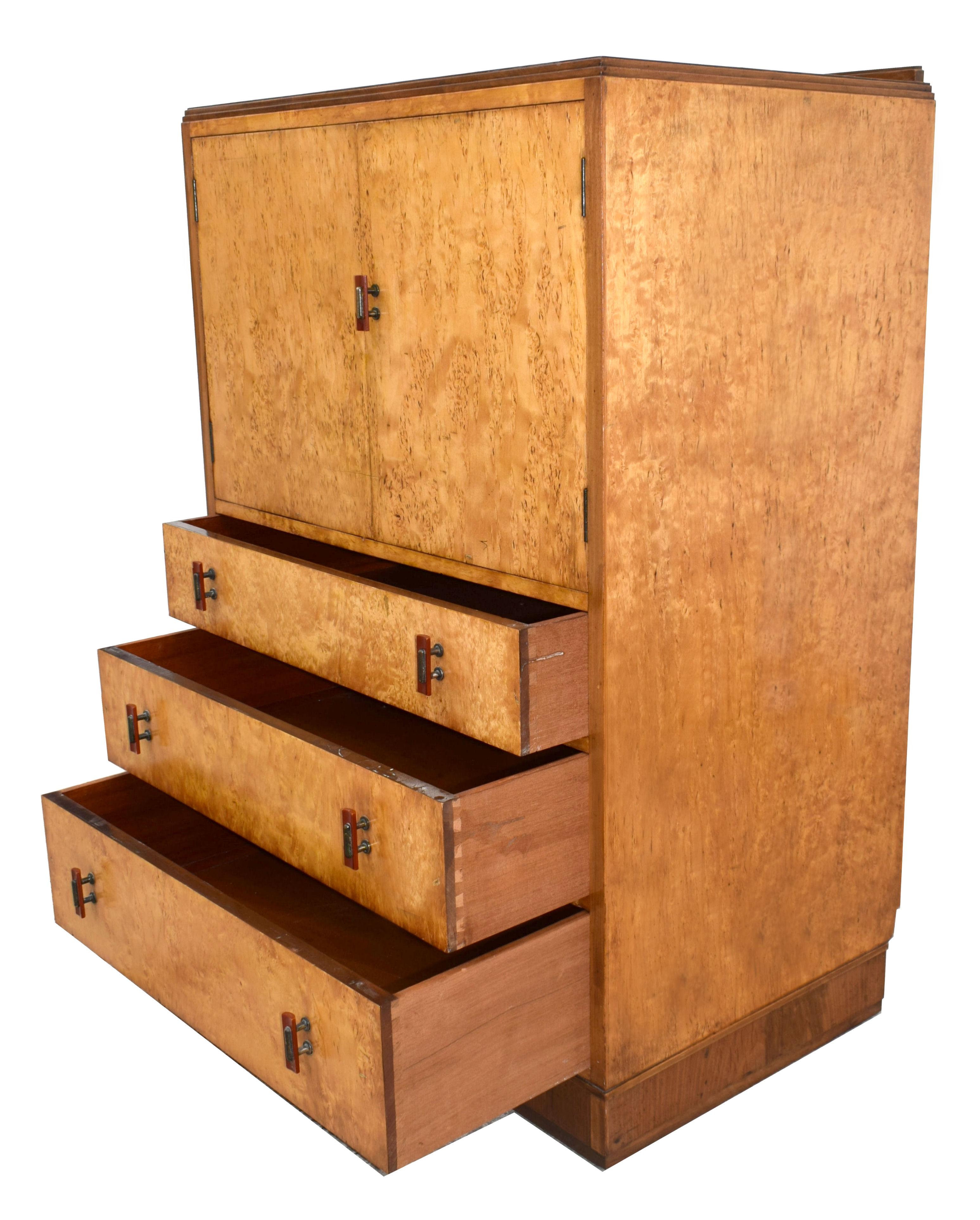 For your consideration is this English Art Deco blonde bird's-eye Maple two-door, three drawer single-piece tallboy, circa 1930 and in excellent original condition. All resting on a Walnut plinth which continues around the piece and contrasts