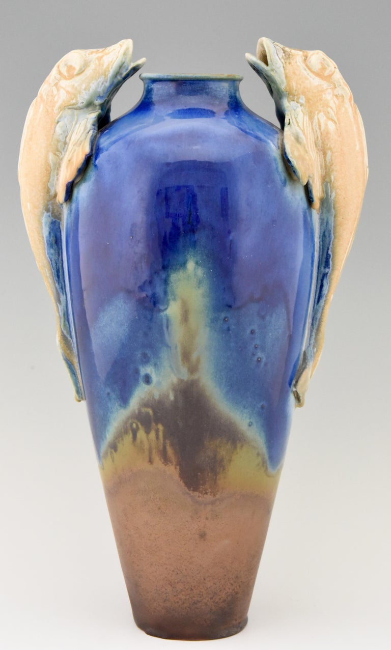 Beautiful tall Art Deco vase with fish handles in blue, beige and terracotta brown glazed ceramic. Attributed to Gilbert Méténier. Marked BR for Bourg La Bresse, France, 1925.
  