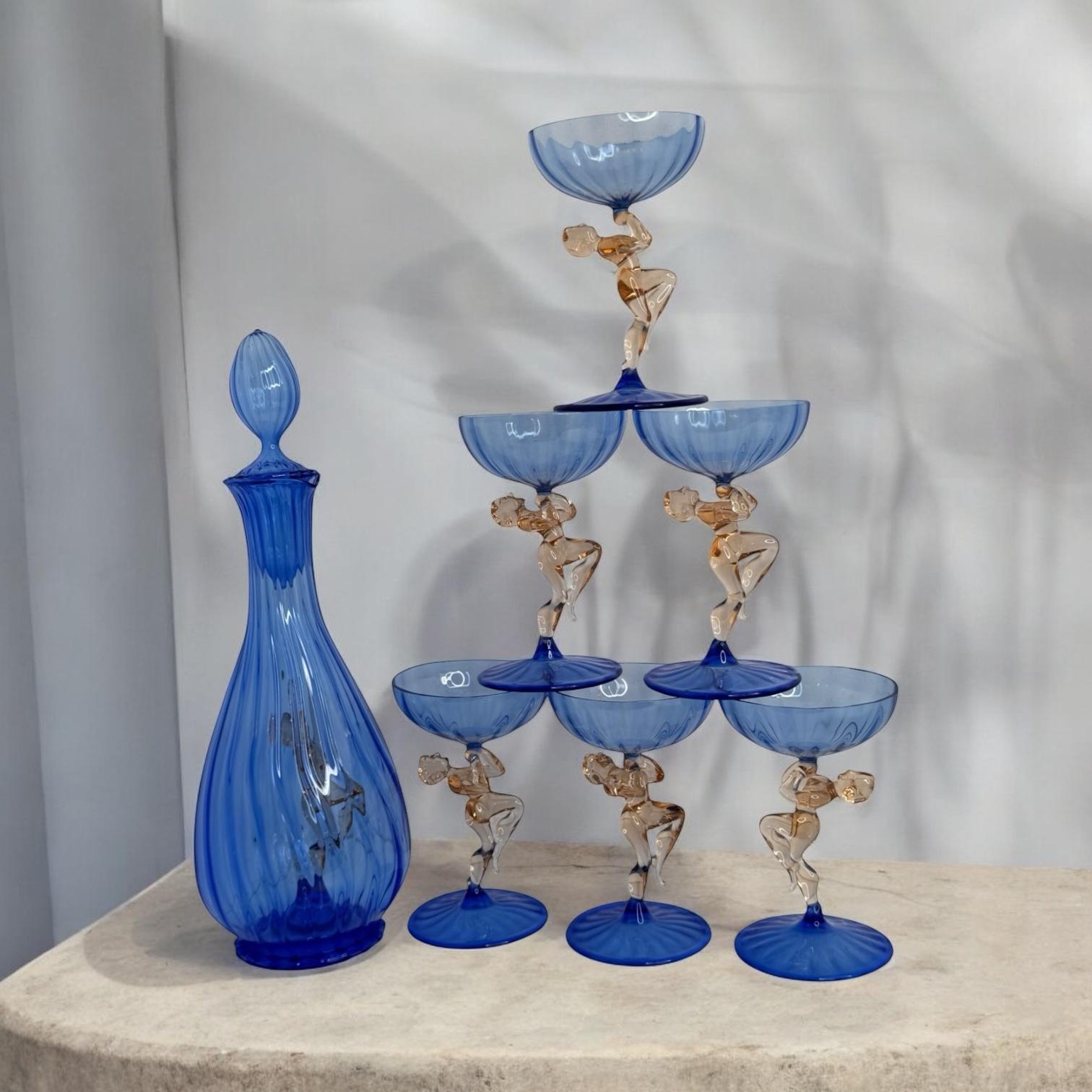 
A slightly cheeky Art Deco decanter set with matching set of six glasses in handblown blue glass, in the style of Bimini. The stems designed as nude girls. Very delicate to touch and amazing that something like this last all these years. This