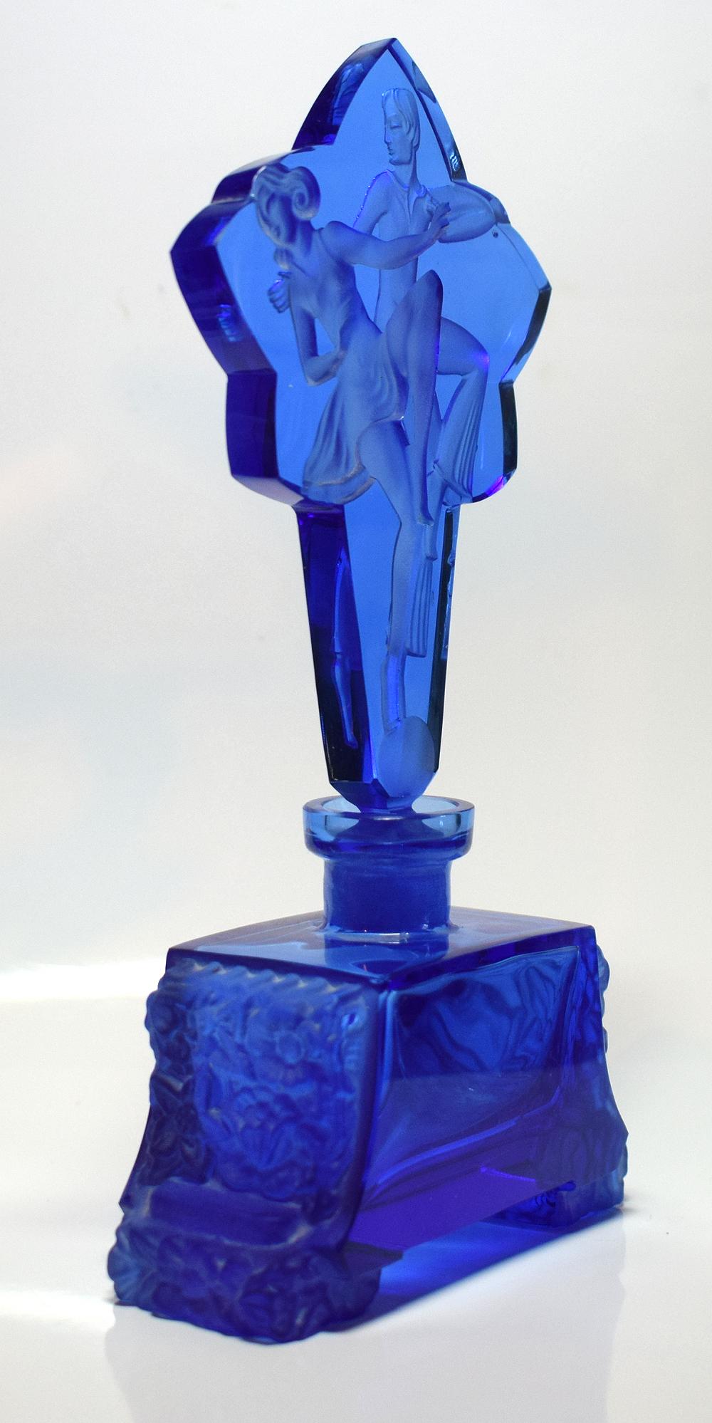 For your consideration is this impressively tall Art Deco style Bristol blue glass perfume bottle. Depicts two dancers on the stopper and an embossed foliage design to the base. Lovely item with no damage, just minor signs of use.